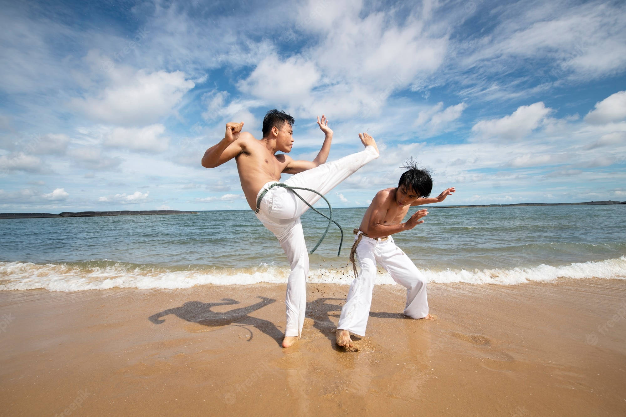 Dance 桌布 壁紙 — 兩名赤膊男子身穿白色長褲，在沙灘上練習武術，背景有海浪和明亮的藍天。