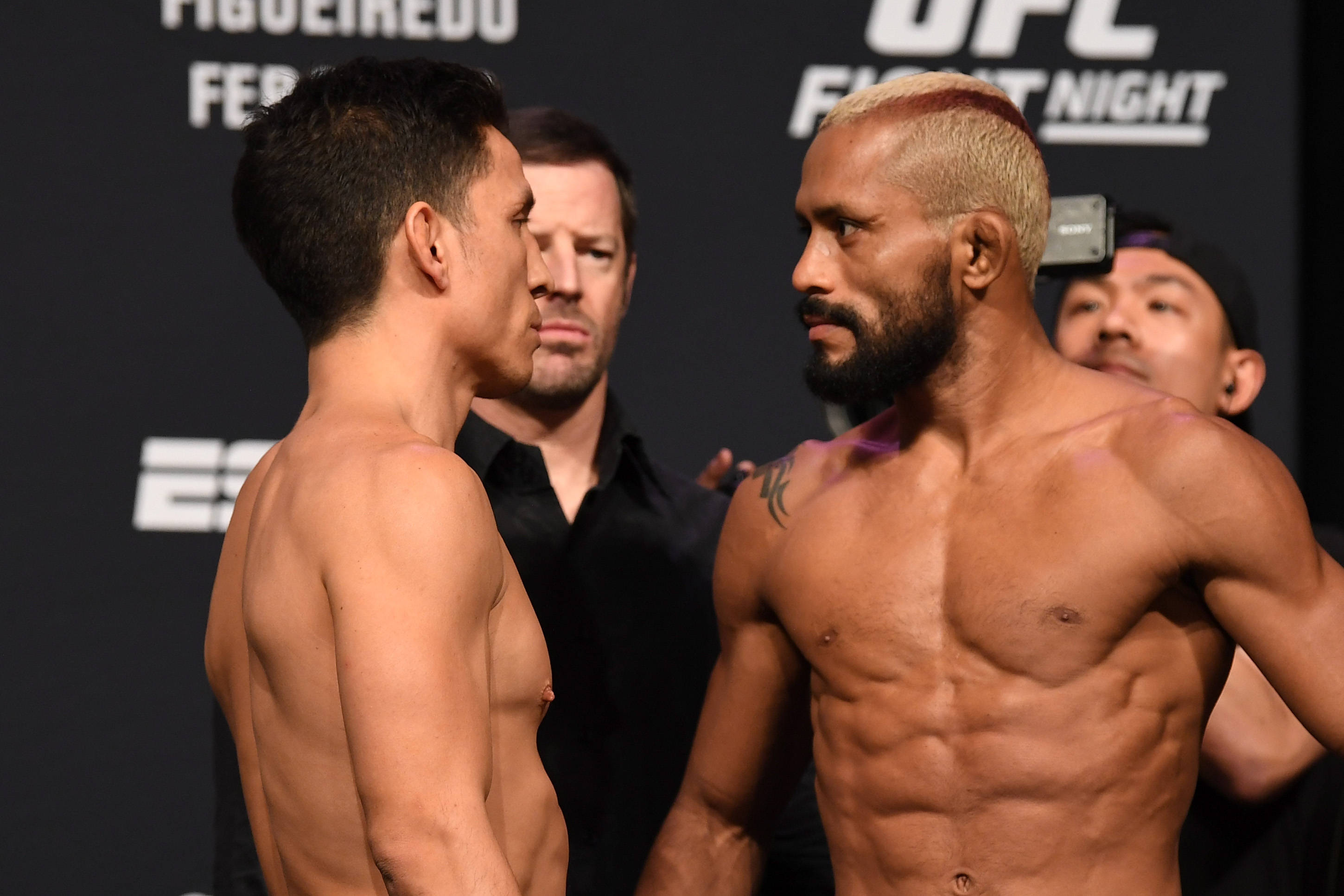 UFC 桌布 壁紙 — 兩名赤裸上身的UFC拳手在明亮的場館燈光下，於賽前對峙中互相怒視。