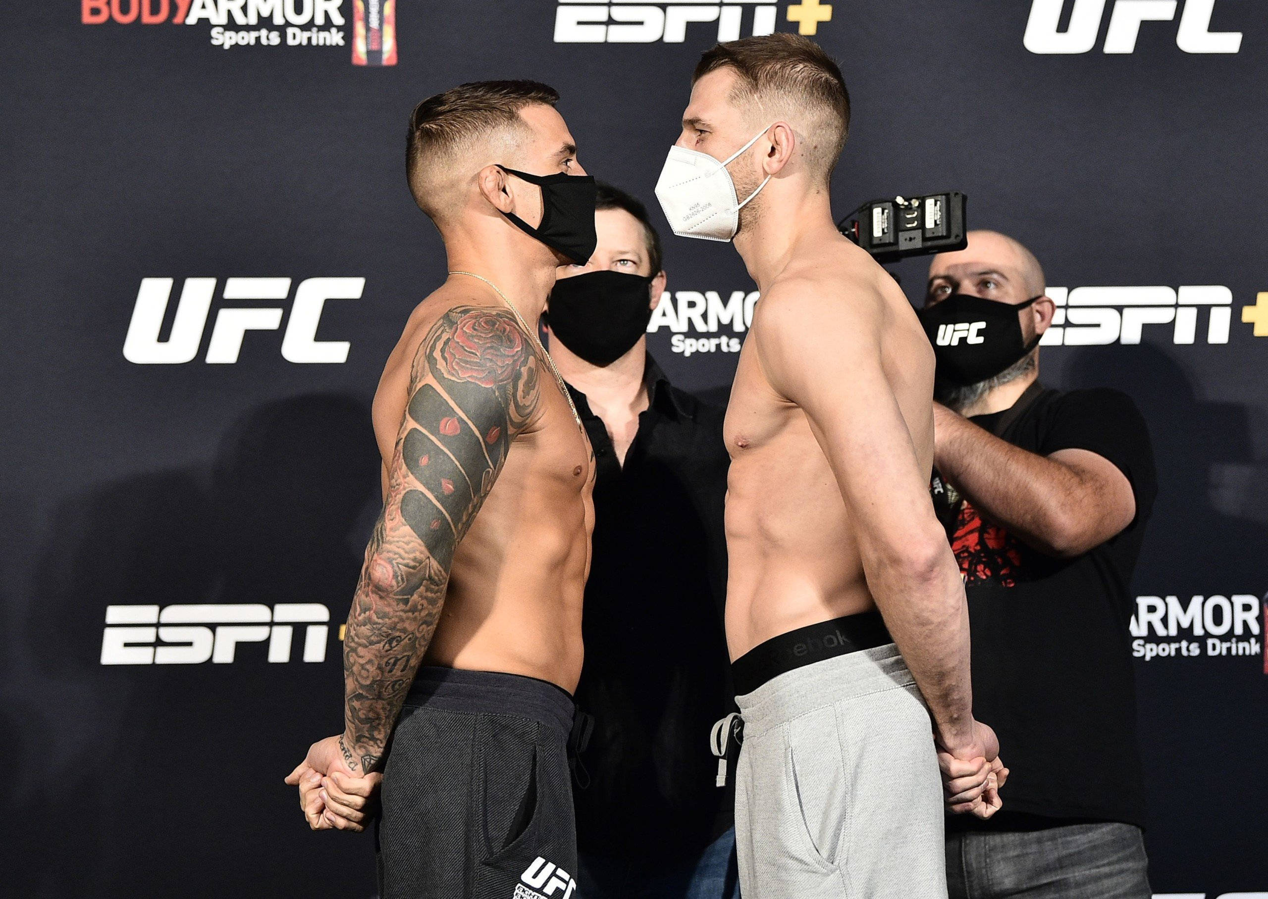UFC 桌布 壁紙 — 兩名赤裸上身的UFC拳手在稱重時對峙，戴著口罩，身後有ESPN和BodyArmor標誌。