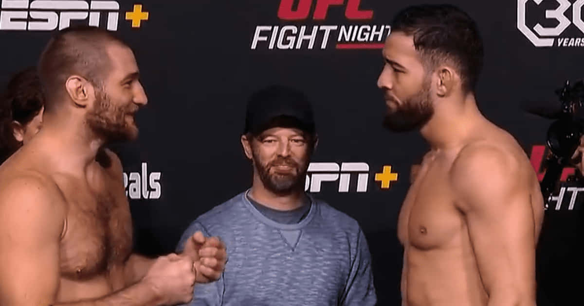 MMA 桌布 壁紙 — 兩名赤裸上身的UFC拳手在記者會上對峙，中間有裁判，背景為品牌佈景。