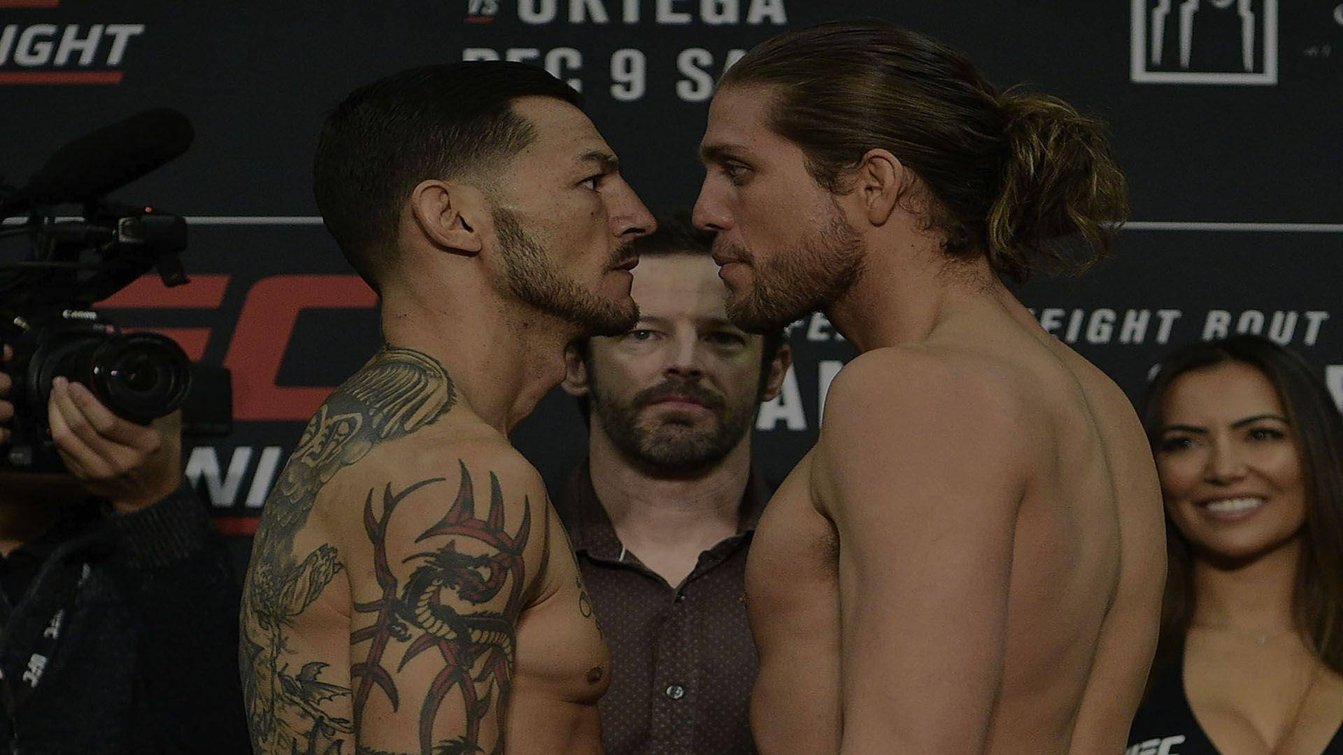 Brian Ortega 桌布 壁紙 — 兩名赤裸上身的男性拳手在UFC過磅中激烈對峙，周圍閃光燈不斷。