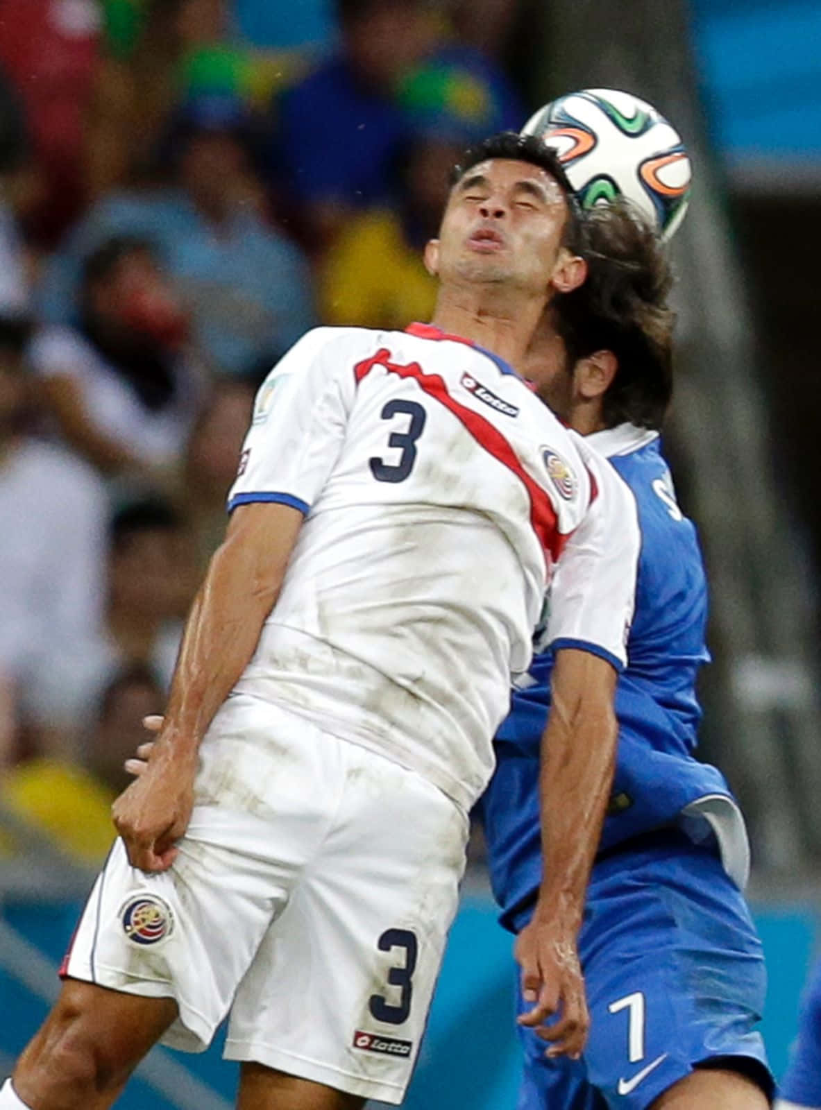 Soccer Ball 桌布 壁紙 — 兩名足球員在體育場燈光下激烈跳起，爭頂一個色彩繽紛的球，進行一場競爭激烈的比賽。