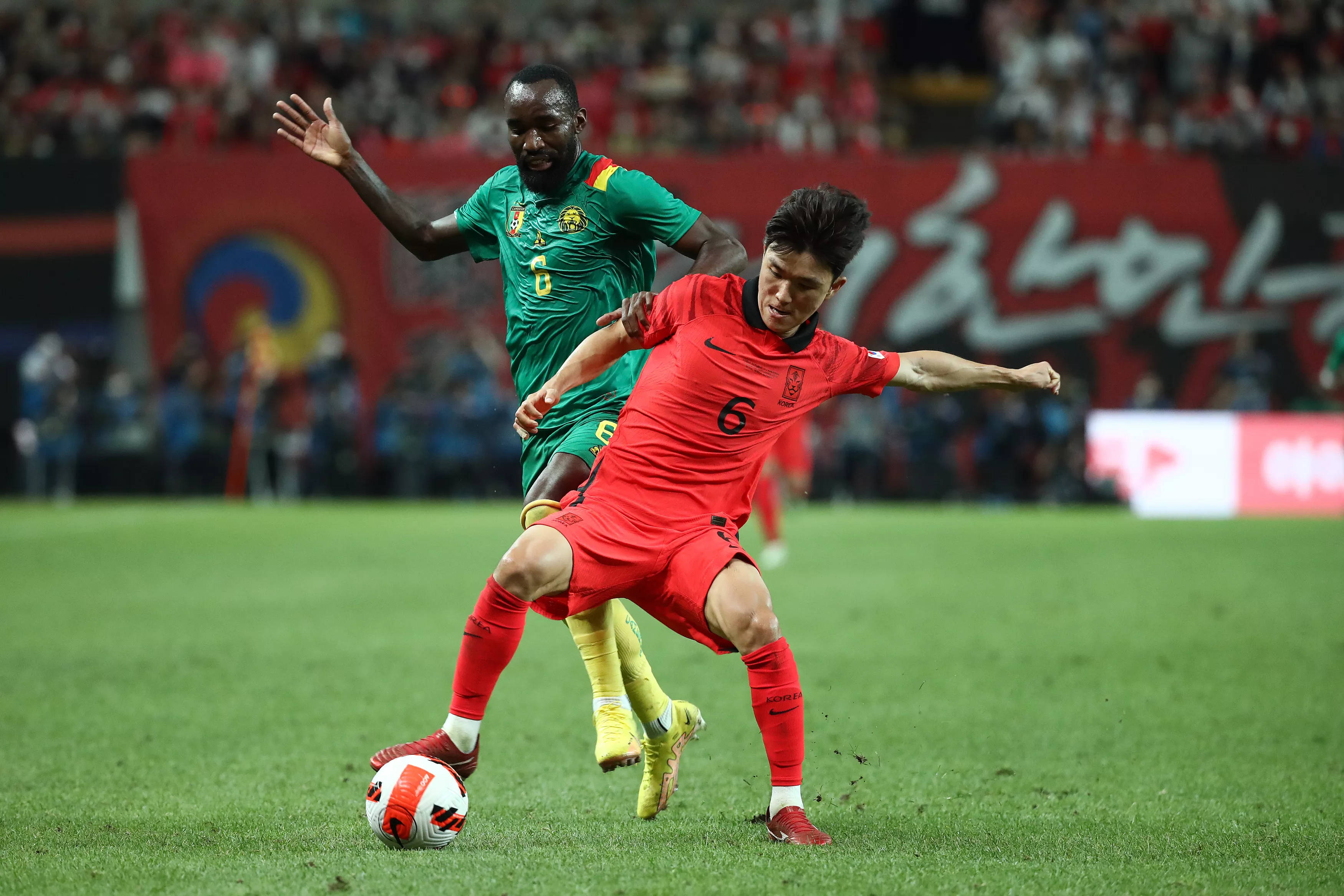 Football Players 桌布 壁紙 — 兩名足球運動員在體育場燈光下，於充滿活力的綠色球場上激烈爭球。