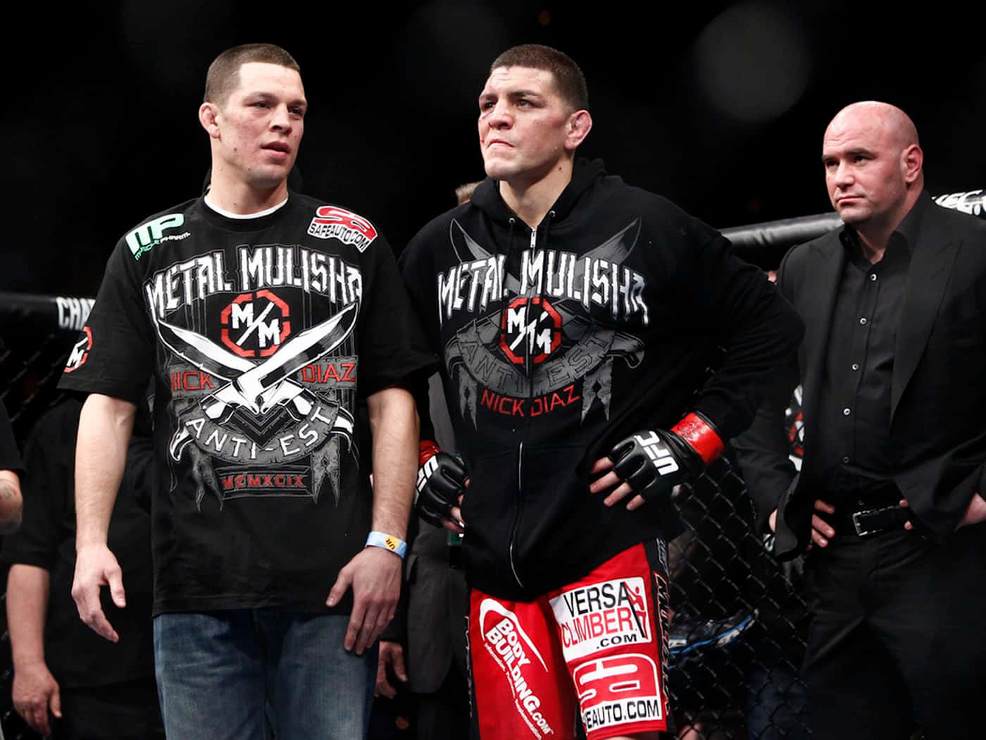 UFC 桌布 壁紙 — 兩名身穿「Metal Mulisha」裝備的拳手在燈光昏暗的MMA八角籠中緊張地站立，附近有一名裁判。