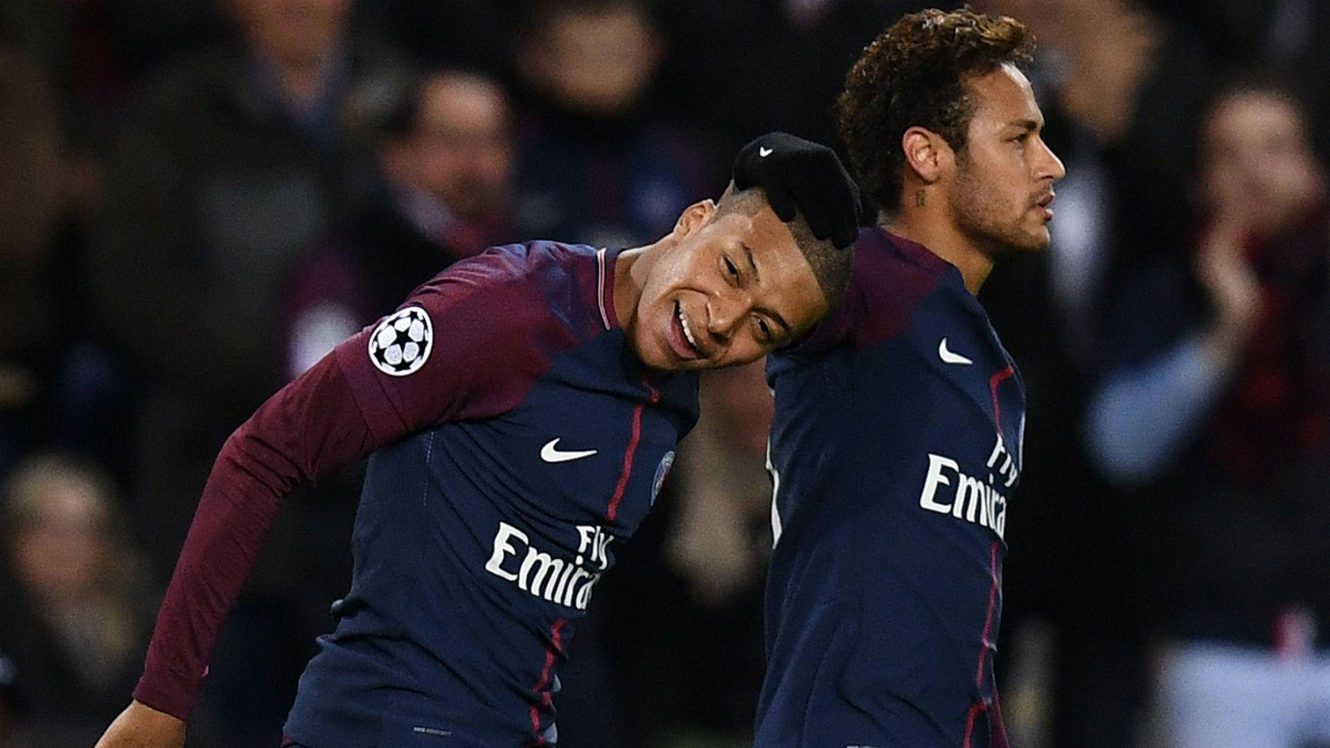 Kylian Mbappe 桌布 壁紙 — 兩名身穿PSG球衣、面帶微笑的足球運動員在明亮的燈光下於球場上緊密慶祝。