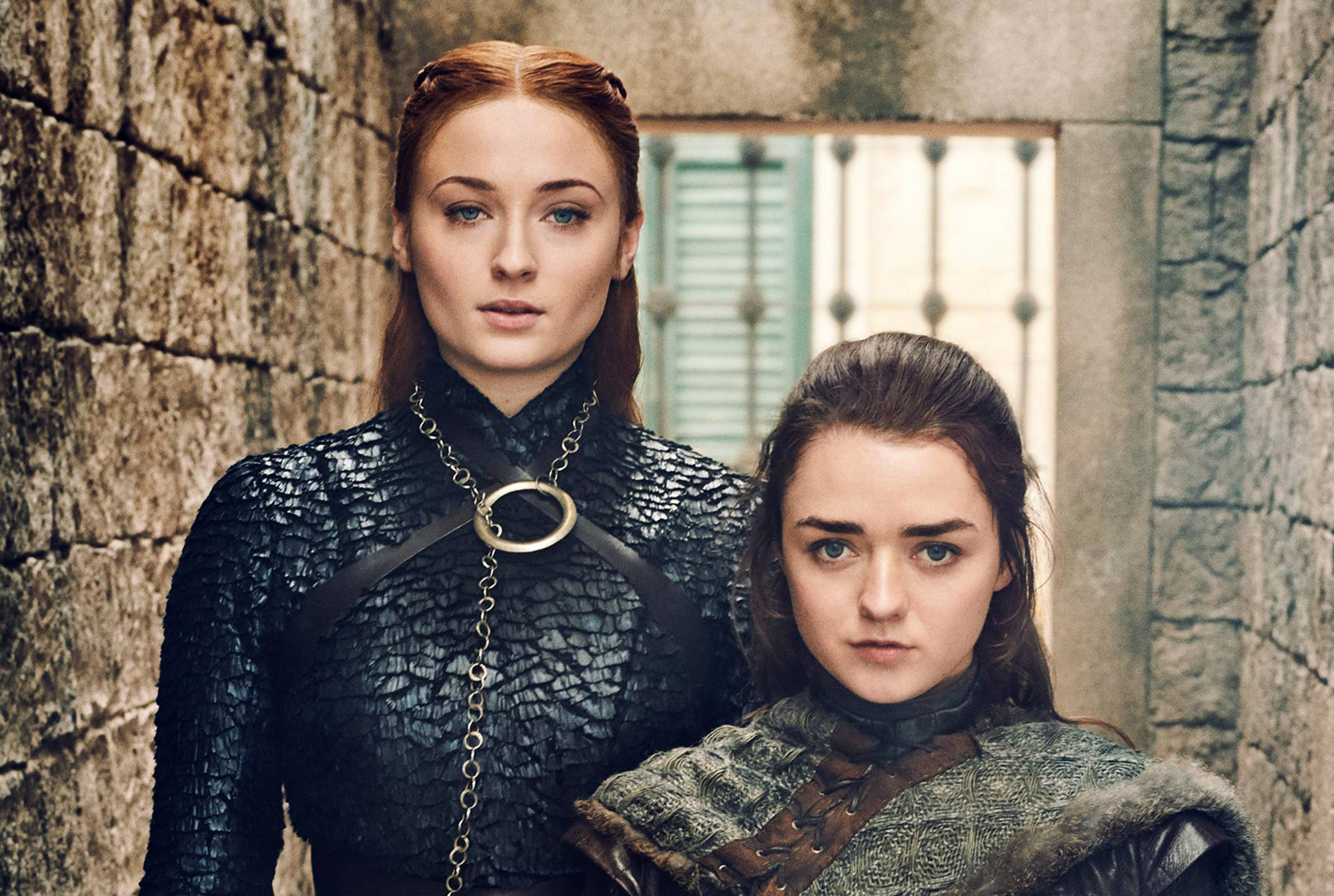 Sansa Stark 桌布 壁紙 — 兩名身穿中世紀盔甲的兇猛女性莊嚴地站在一面風化的石牆前，身後有一扇帶欄杆的窗戶。
