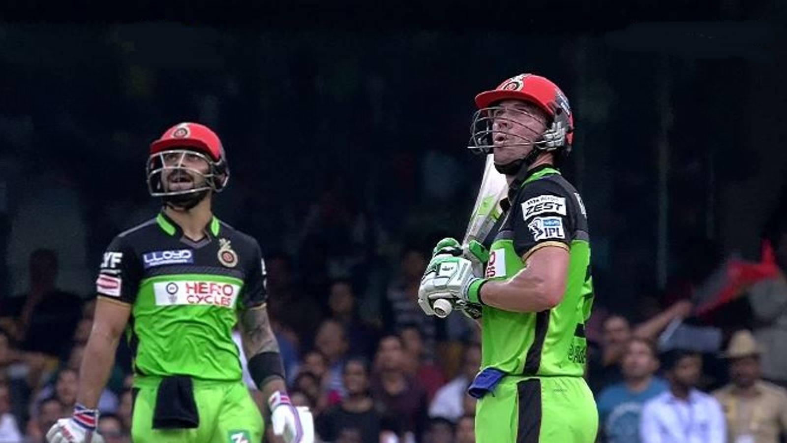 royal challengers bangalore 桌布 壁紙 — 兩名身穿亮綠色球衣的板球運動員在體育場燈光下高舉球棒慶祝。