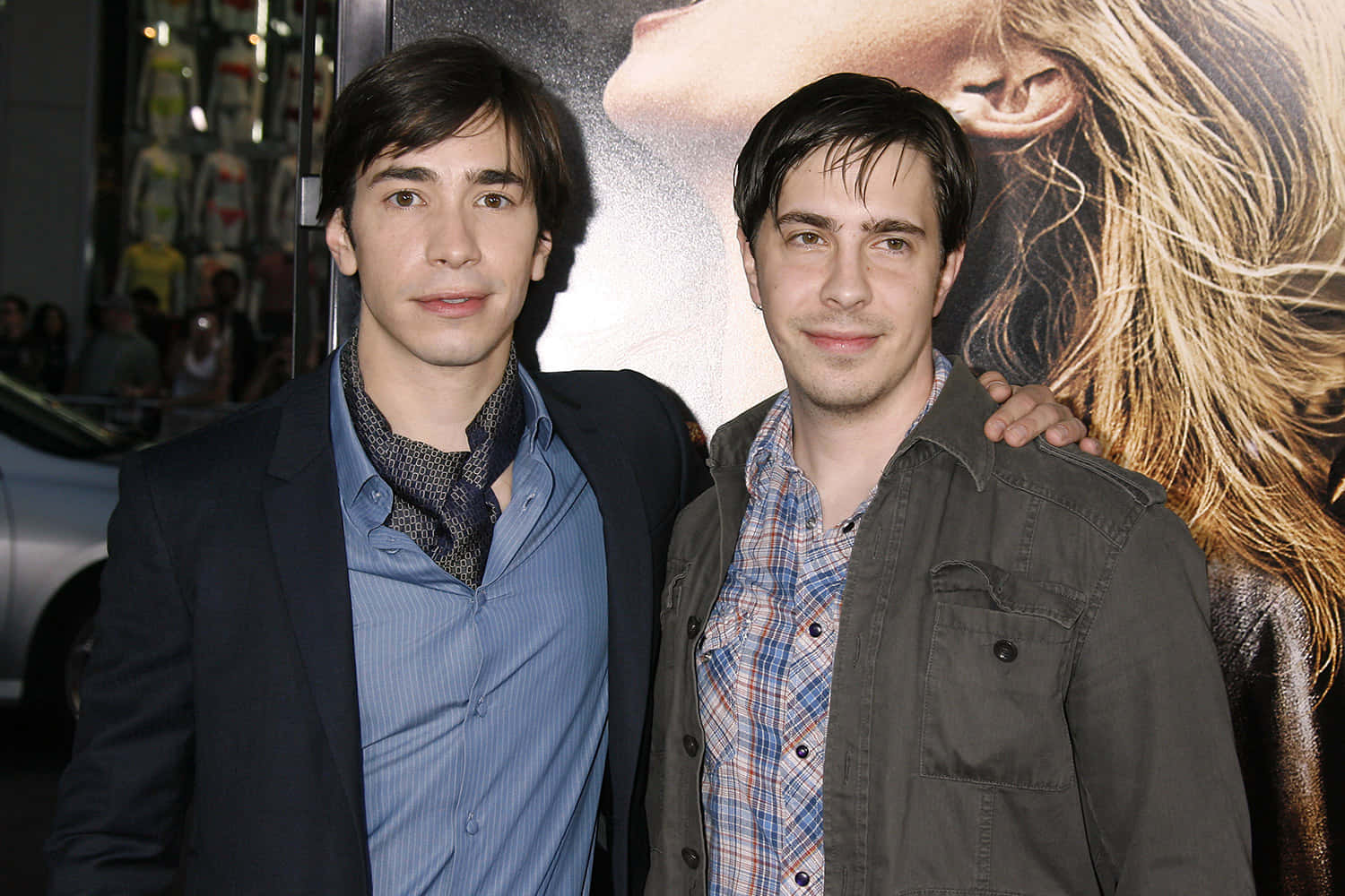 Justin Long 桌布 壁紙 — 兩名身穿休閒外套的男子在電影首映會上一起擺姿勢，身後有一張大型宣傳海報。