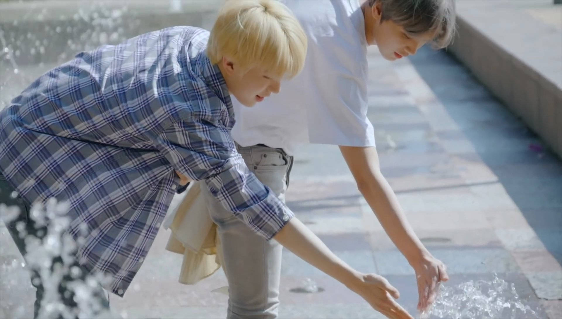 Nct 桌布 壁紙 — 兩名身穿休閒服的年輕男子在陽光普照的瓷磚小徑上嬉戲地潑水。