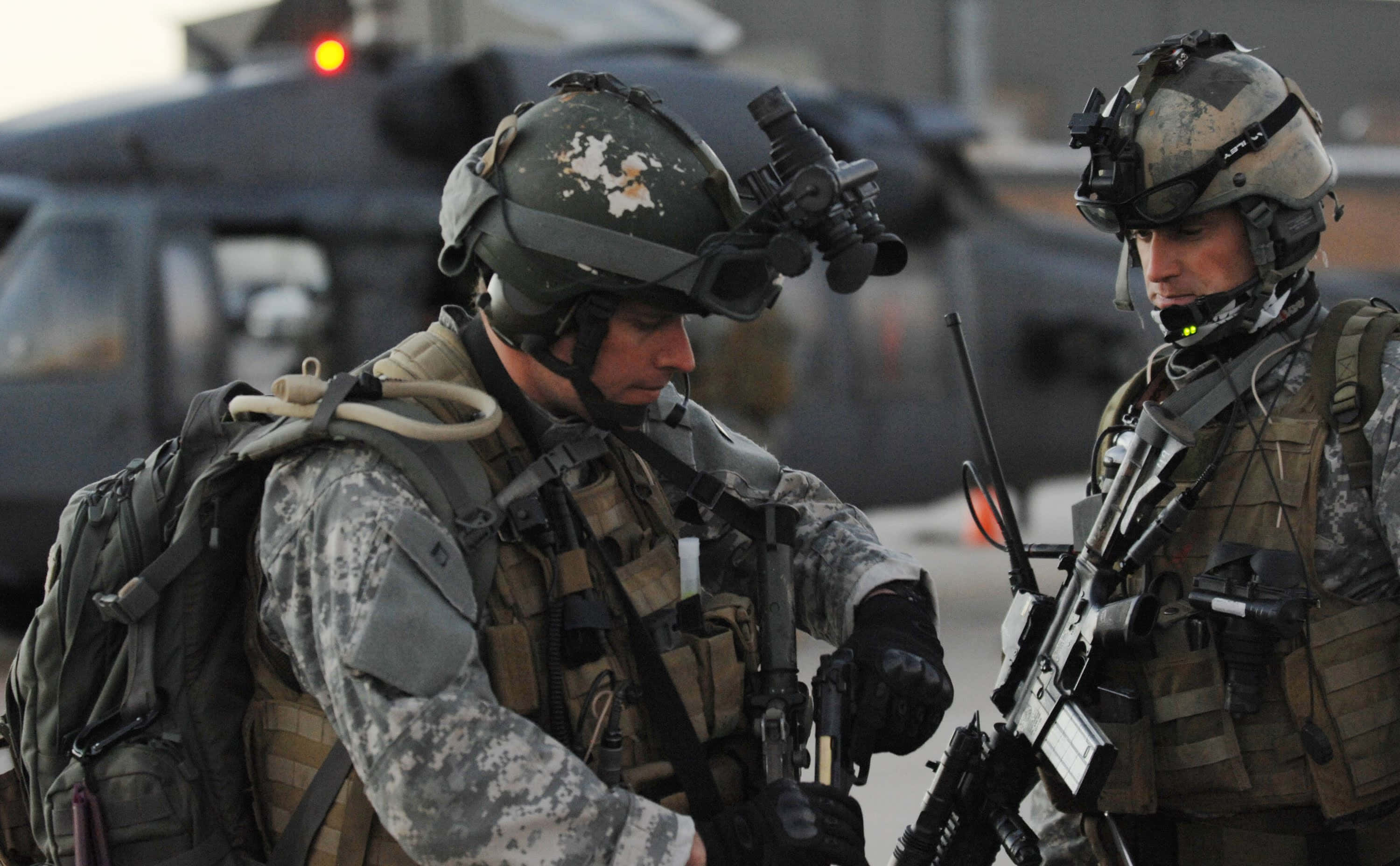 Special Forces 桌布 壁紙 — 兩名身穿全副戰鬥裝備的士兵在任務期間帶著專注的表情站在直升機附近。