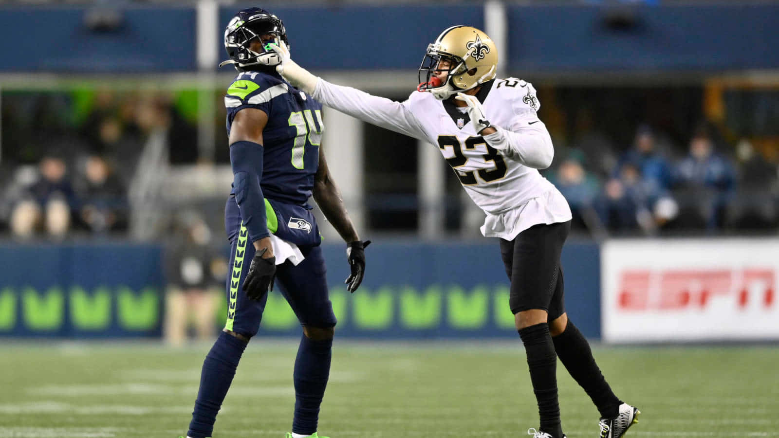 New Orleans Saints 桌布 壁紙 — 兩名身穿全套裝備的NFL球員在夜間比賽期間，在燈光明亮的足球場上互相擊掌。