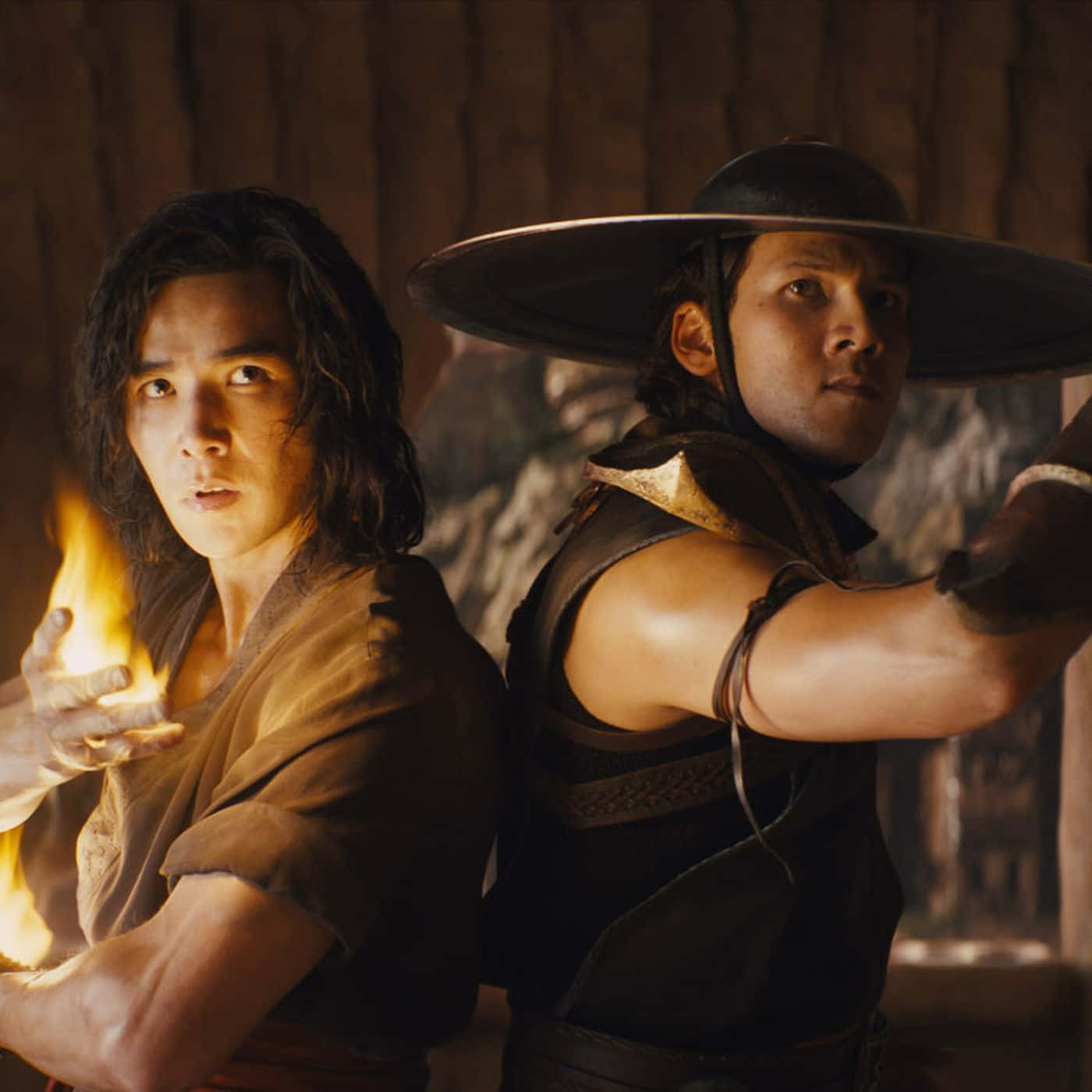 Mortal Kombat Kung Lao 桌布 壁紙 — 兩名身穿古代服飾的戰士緊張地站著，一人揮舞火焰，另一人戴著寬邊帽在昏暗的木製房間中擺好姿勢。