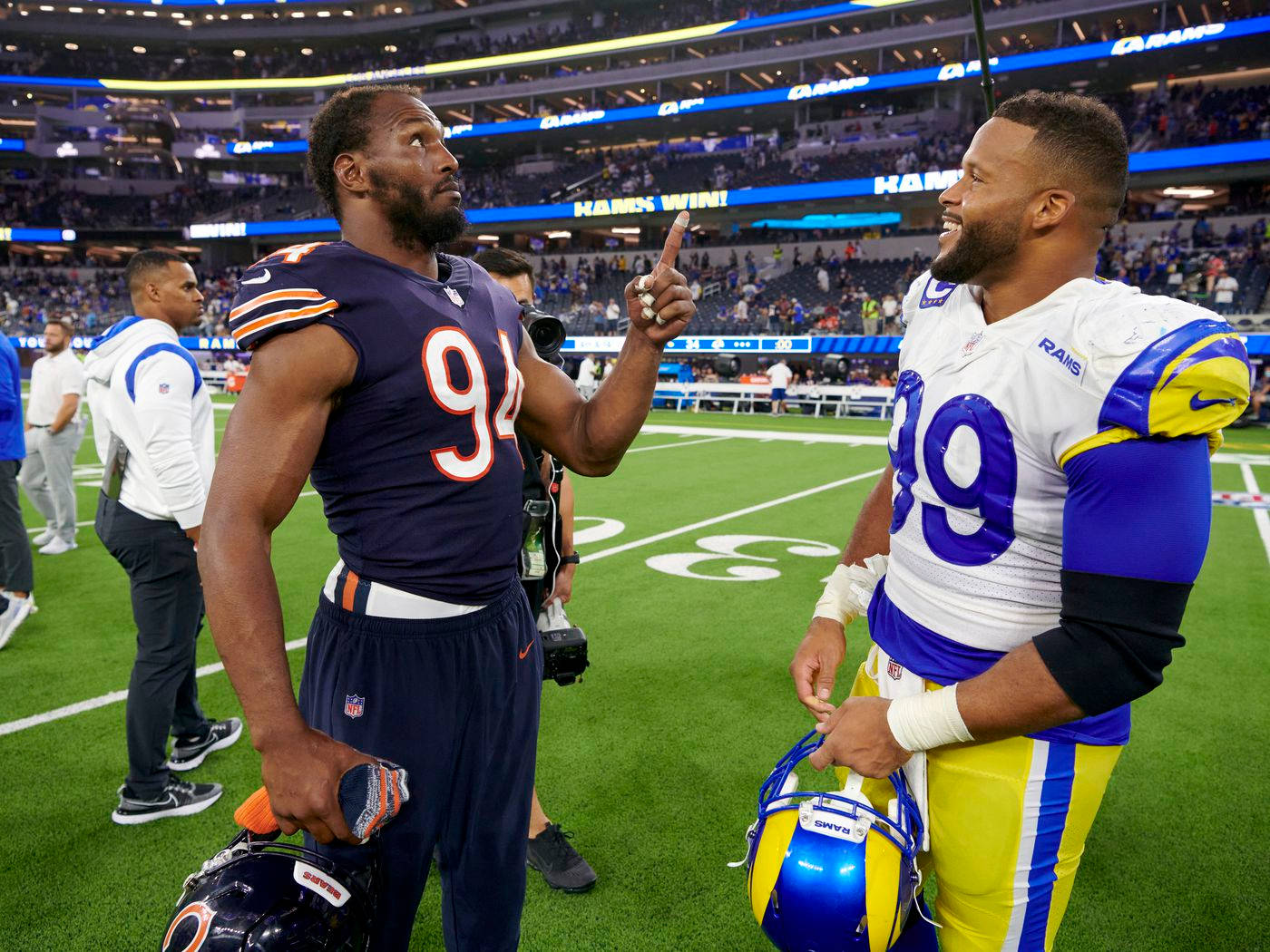 桌布 壁紙 — 兩名身穿對立球衣的NFL球員在比賽結束後，在燈光明亮的球場上互相做出尊重的手勢。