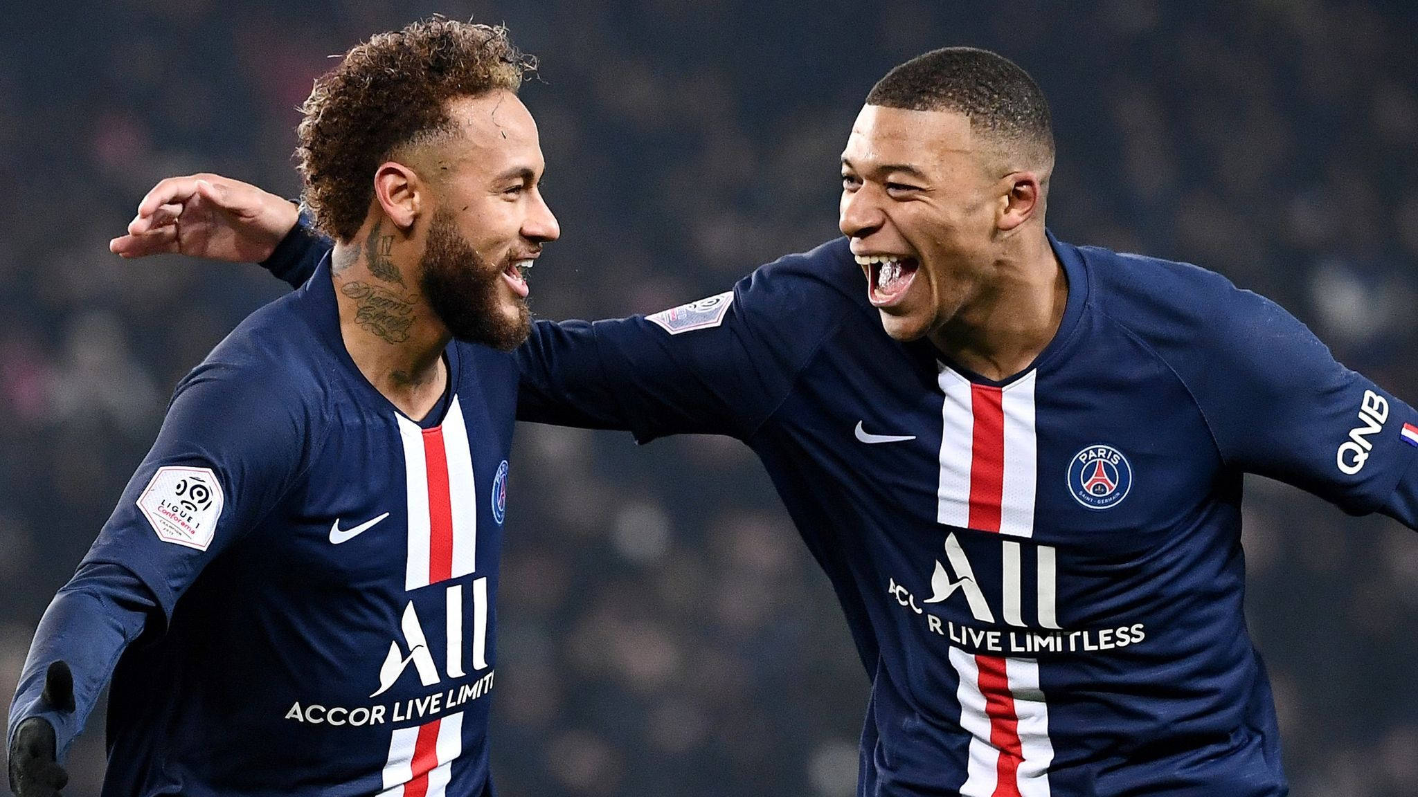 Kylian Mbappe 桌布 壁紙 — 兩名身穿巴黎聖日耳曼球衣的足球員在球場上熱情地互相搭肩慶祝。