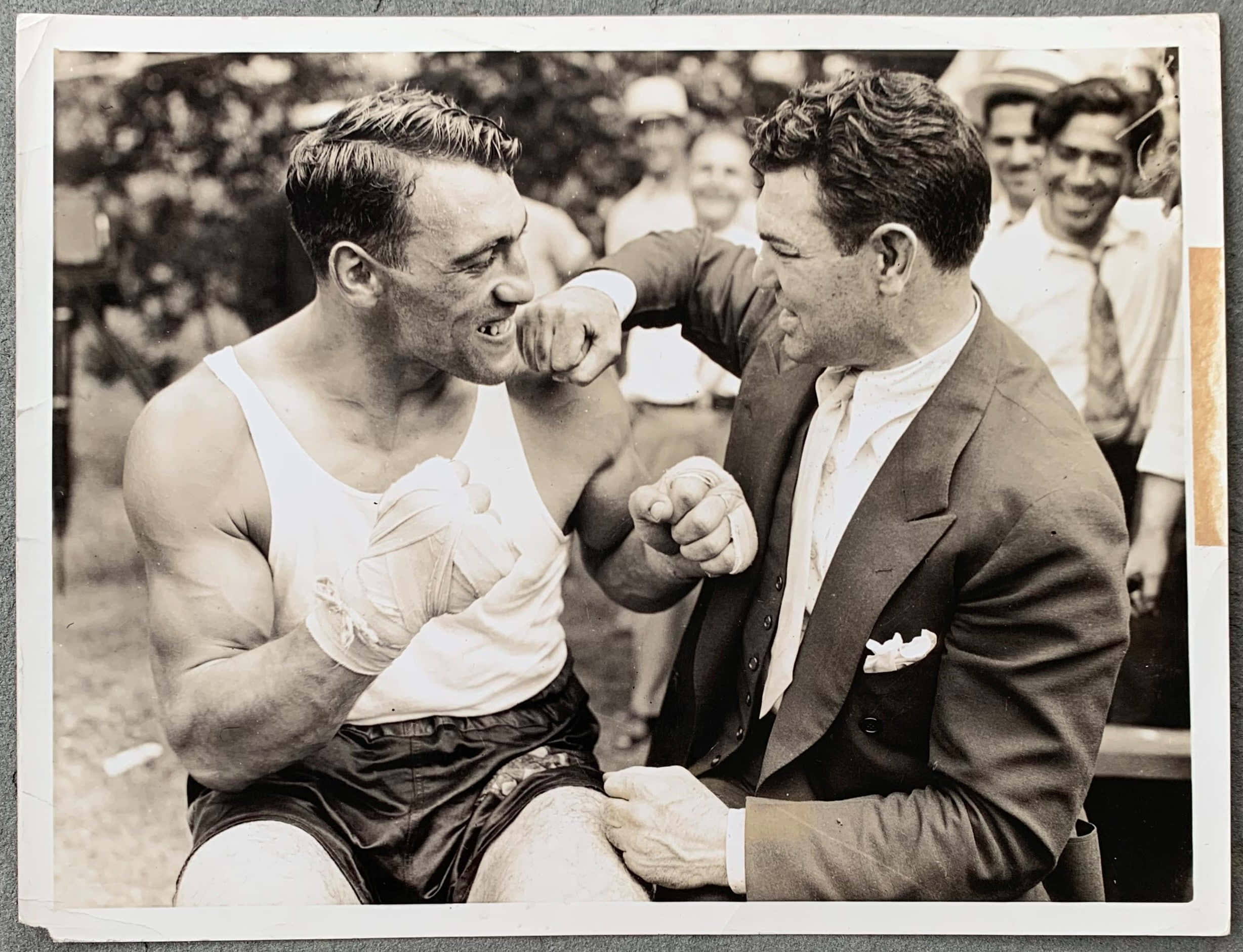 Boxing 桌布 壁紙 — 兩名身穿復古服裝的男子在陽光明媚的戶外環境中，在圍觀人群中以歡樂的強度互相碰拳。