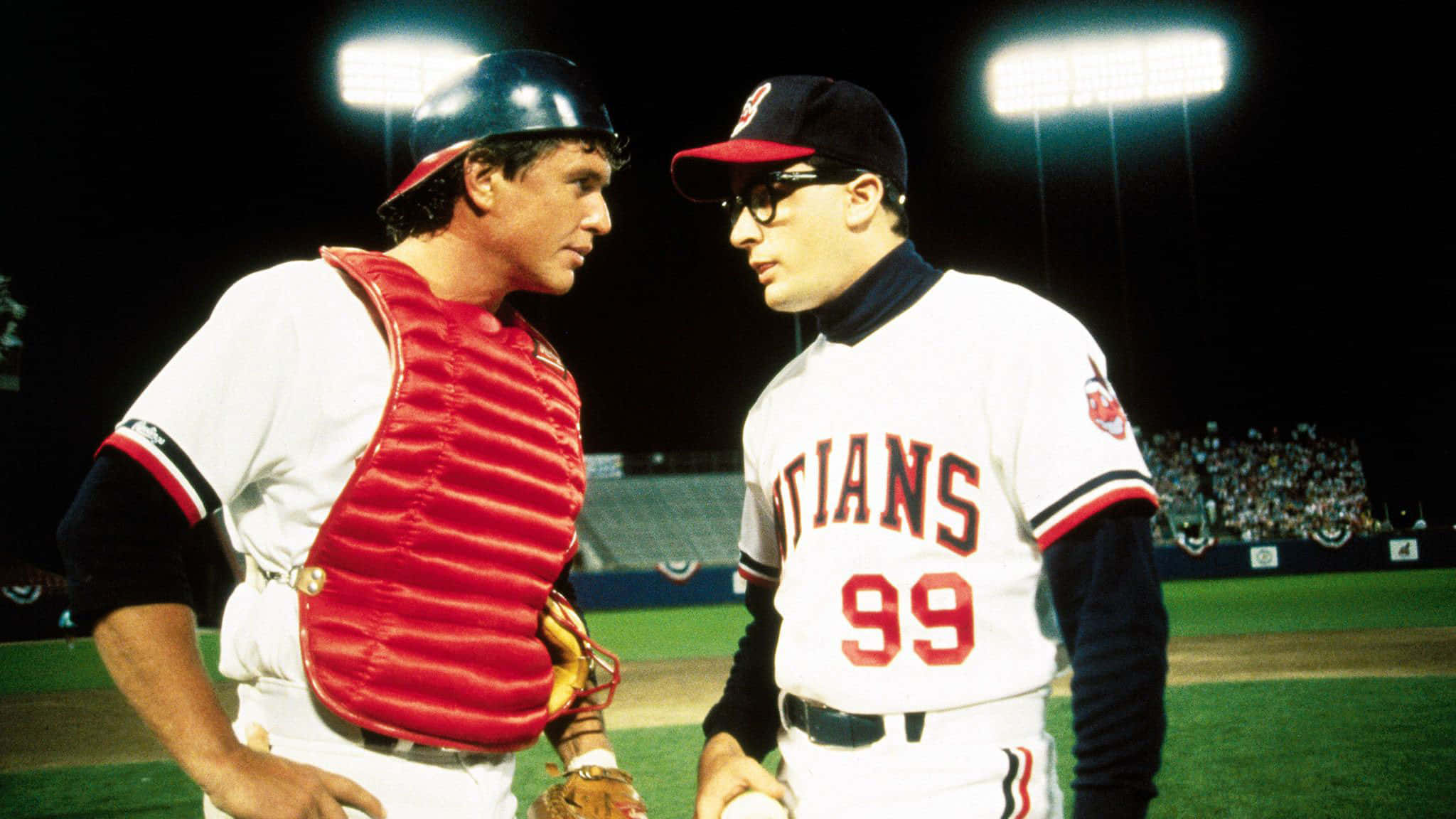 Major League Movie 桌布 壁紙 — 兩名身穿復古球衣的棒球運動員在夜間比賽中於球場燈光下對峙。