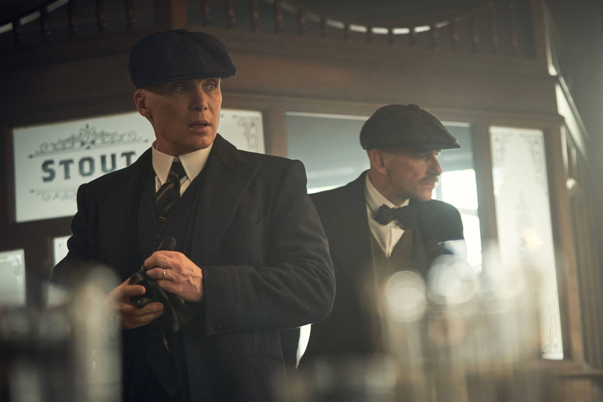 兩名身穿復古西裝和扁帽的男子在光線昏暗的酒吧內。 — Peaky Blinders 壁紙