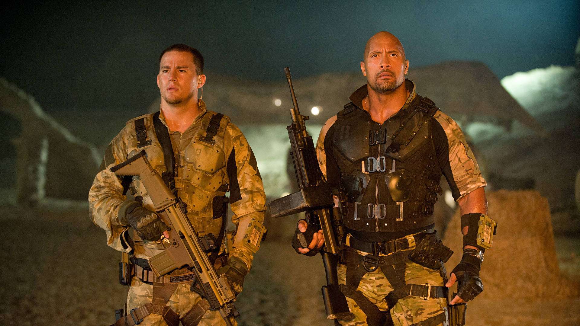 Gi Joe 桌布 壁紙 — 兩名身穿戰術裝備的士兵在夜間於沙漠戰場上，在昏暗的人造燈光下保持警覺。