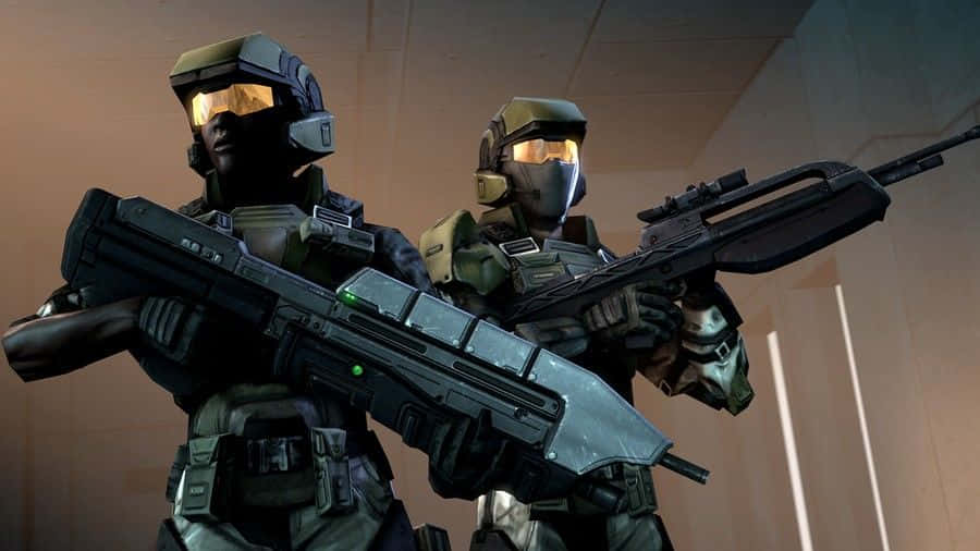 Halo Unsc 桌布 壁紙 — 兩名身穿未來戰鬥裝備的裝甲士兵在光線昏暗的走廊中手持重型武器準備就緒。