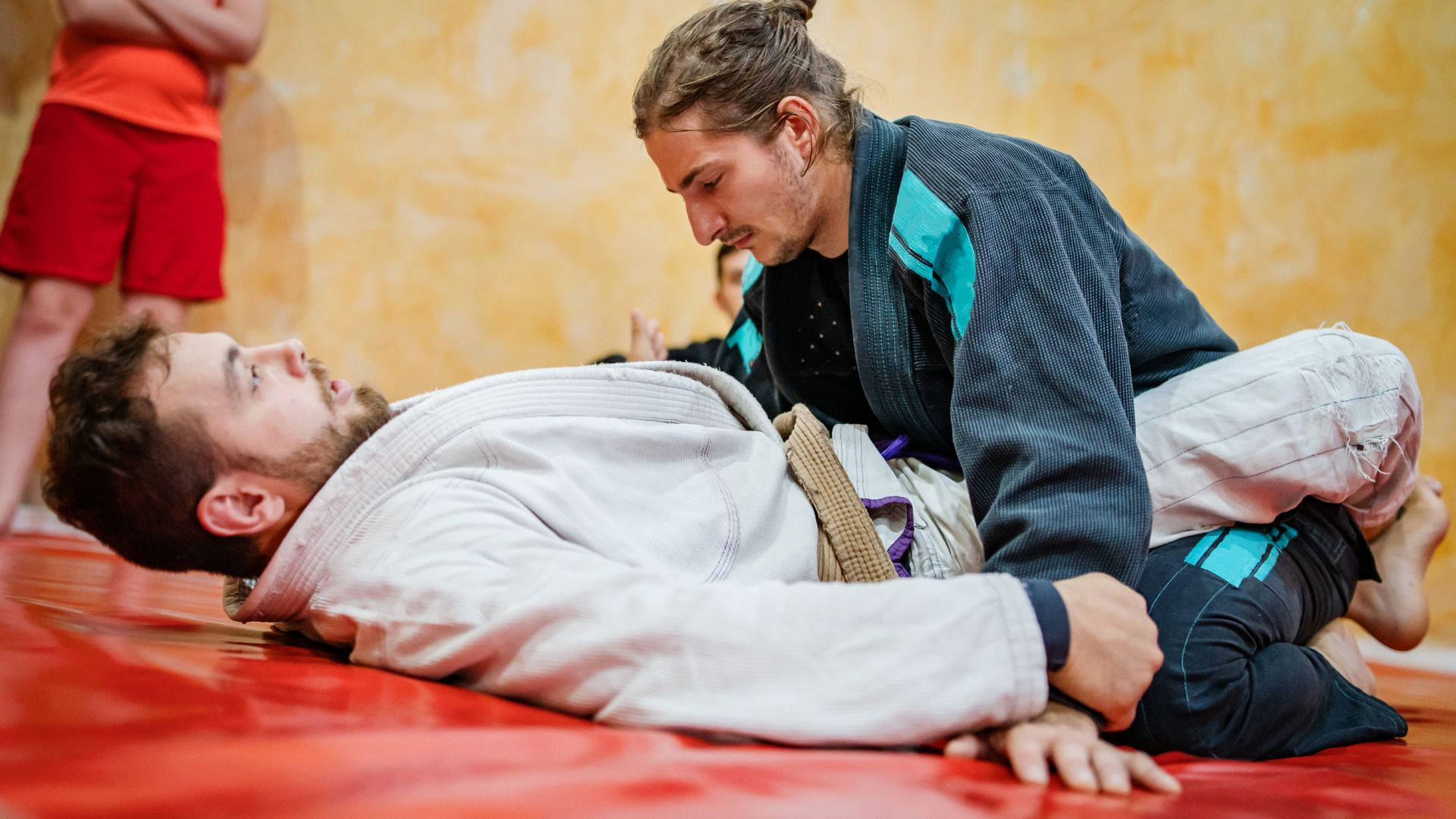 martial arts 桌布 壁紙 — 兩名身穿柔道服的男子在紅色軟墊上激烈糾纏，表情專注，充滿運動張力。