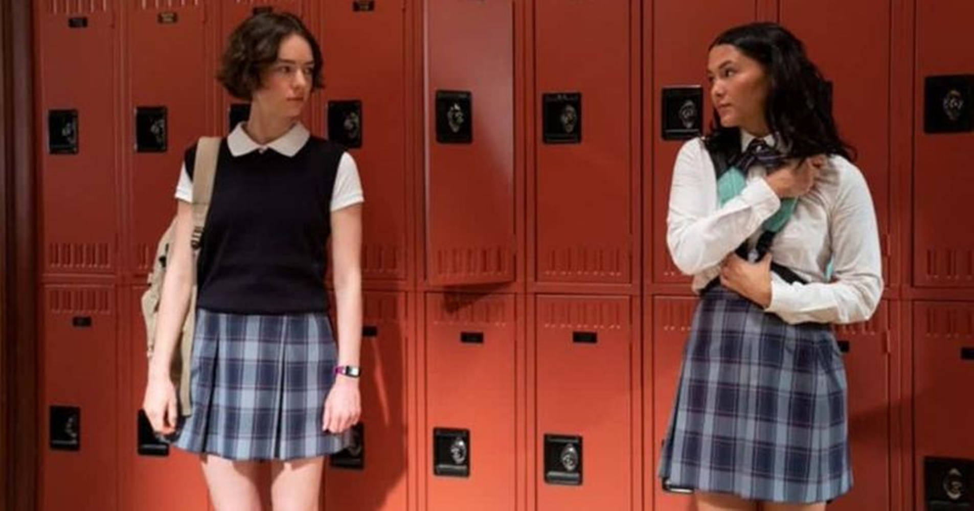 Netflix 桌布 壁紙 — 兩名身穿校服的青少年女孩在走廊中明亮的紅色置物櫃之間面對面站立。