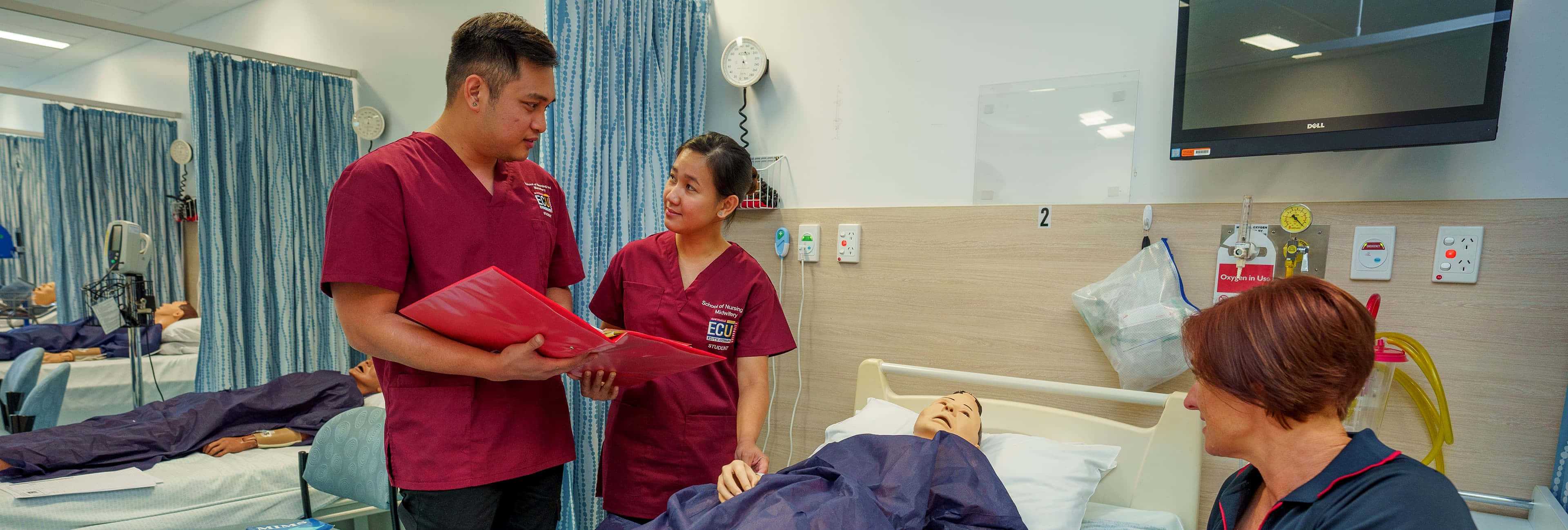 Nursing 桌布 壁紙 — 兩名身穿棗紅色制服嘅護士喺病床旁邊查閱病人嘅病歷，而另一名護士喺附近照顧另一位病人。