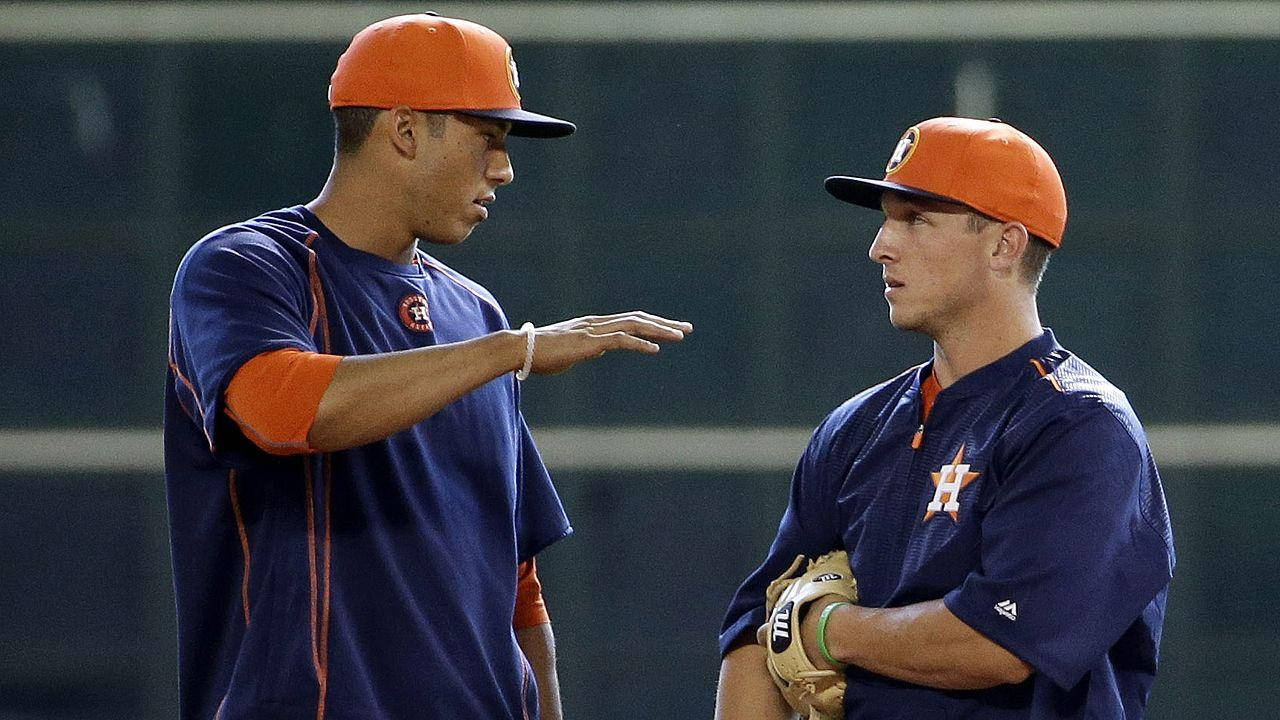 Bregman 桌布 壁紙 — 兩名身穿橙色和藍色球衣的棒球運動員在球場燈光下進行訓練時激烈交談。