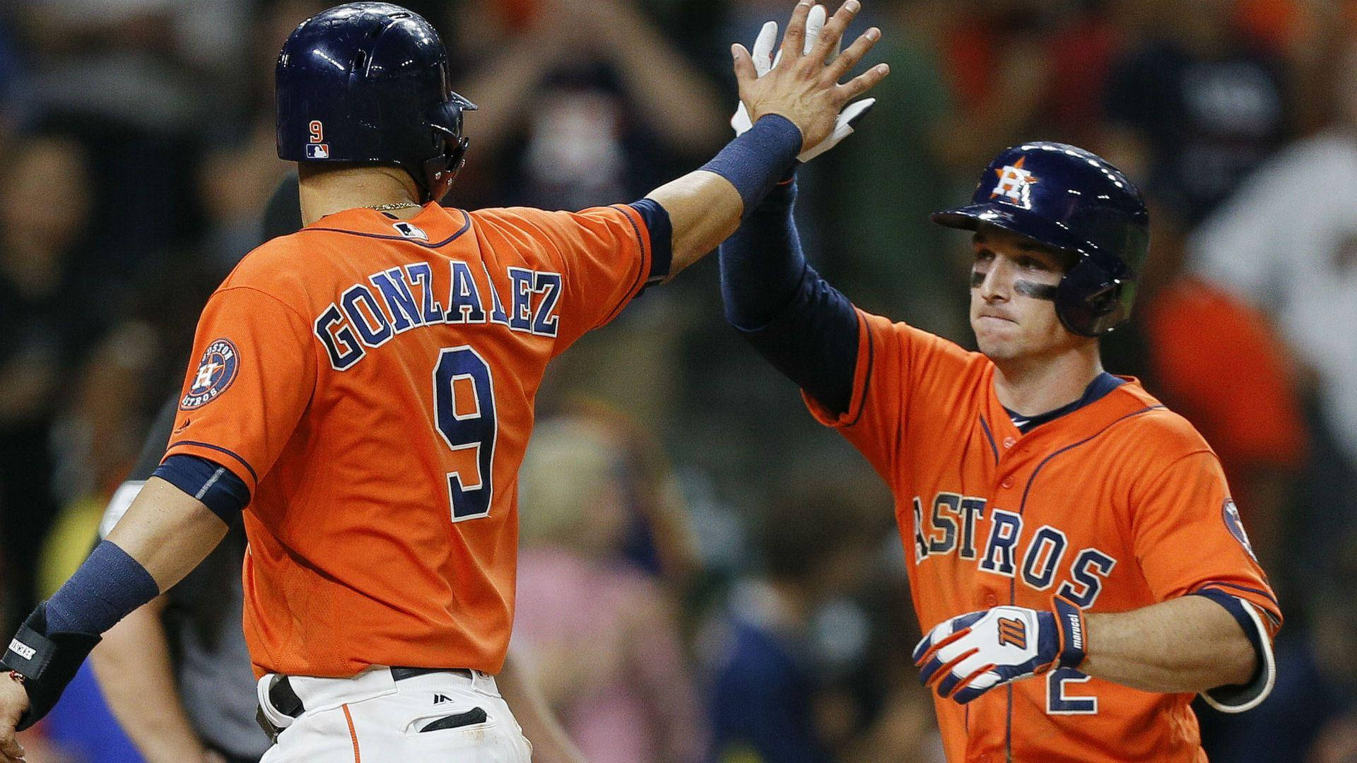 Bregman 桌布 壁紙 — 兩名身穿橙色球衣的休士頓太空人棒球運動員在夜間比賽中於球場燈光下擊掌。