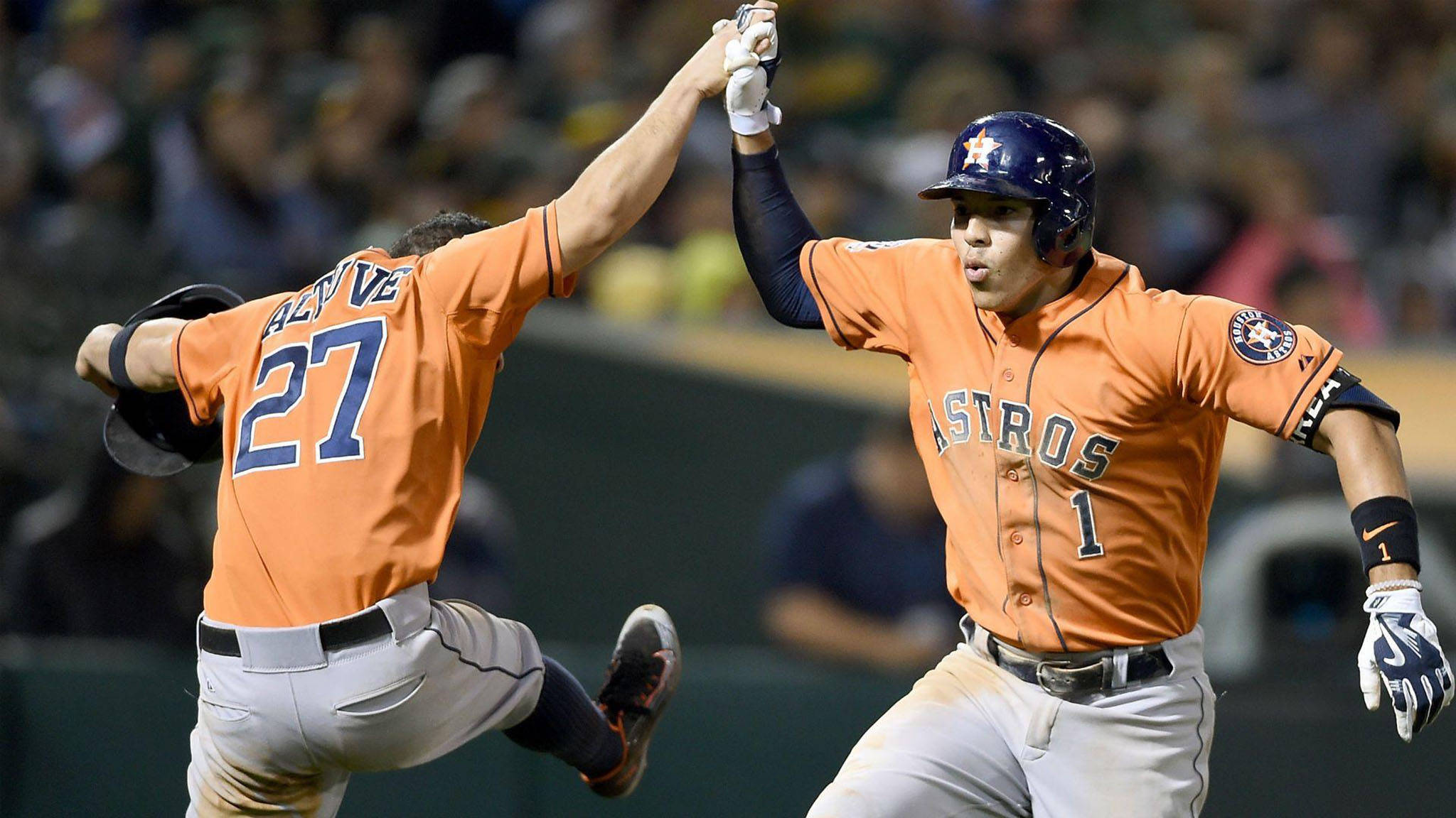 Carlos Correa 桌布 壁紙 — 兩名身穿橙色球衣的休士頓太空人棒球運動員在夜間比賽中擊掌慶祝。