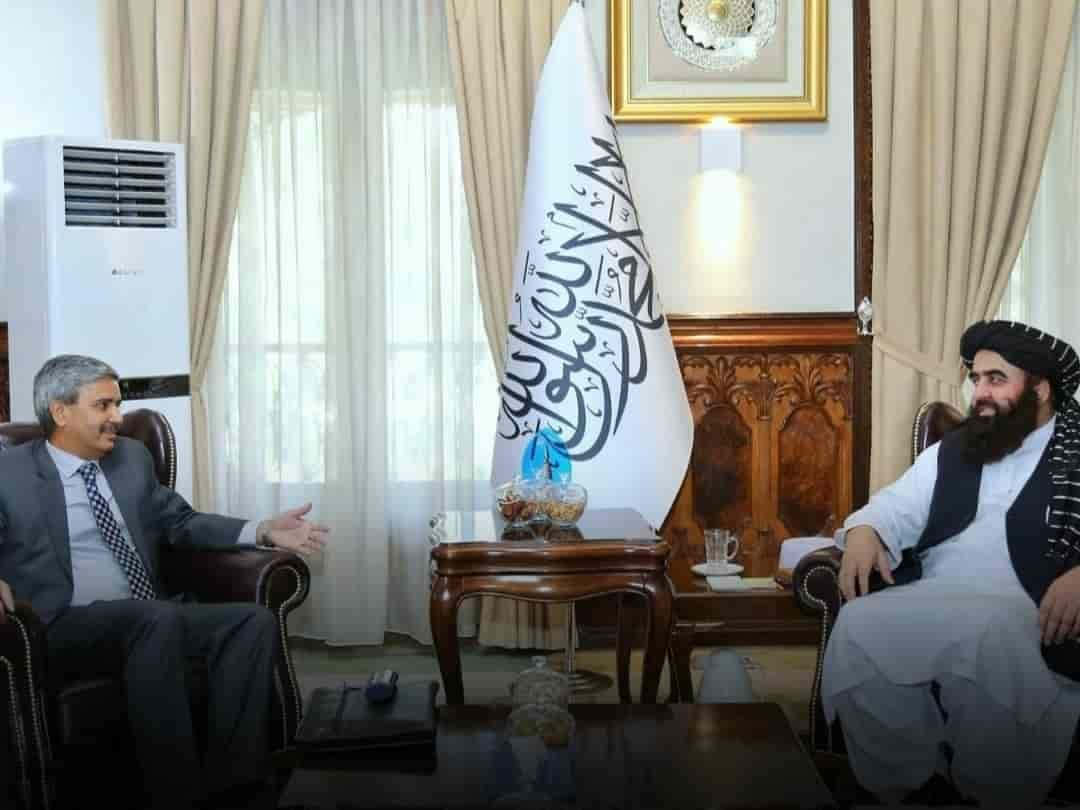 Taliban 桌布 壁紙 — 兩名身穿正式及傳統服飾的男子在一個華麗的房間內相對而坐，中間有一面旗幟。