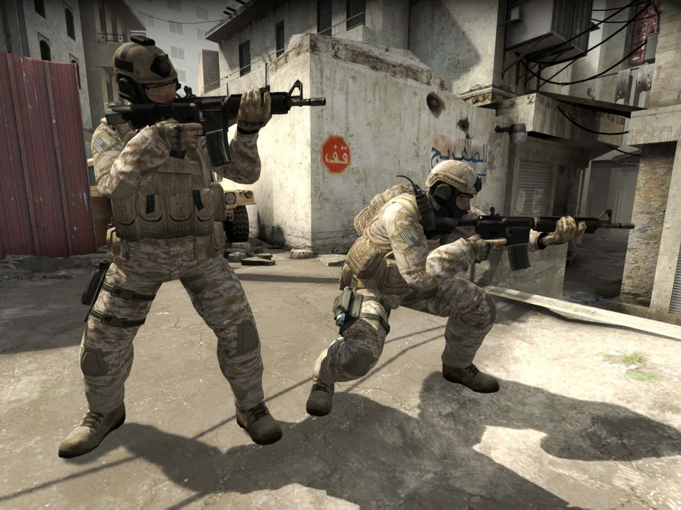 Best Counter-strike Global Offensive 桌布 壁紙 — 兩名身穿沙漠迷彩的士兵在陽光照耀、戰火摧殘的城市小巷中前進，牆壁龜裂，上面有阿拉伯塗鴉。