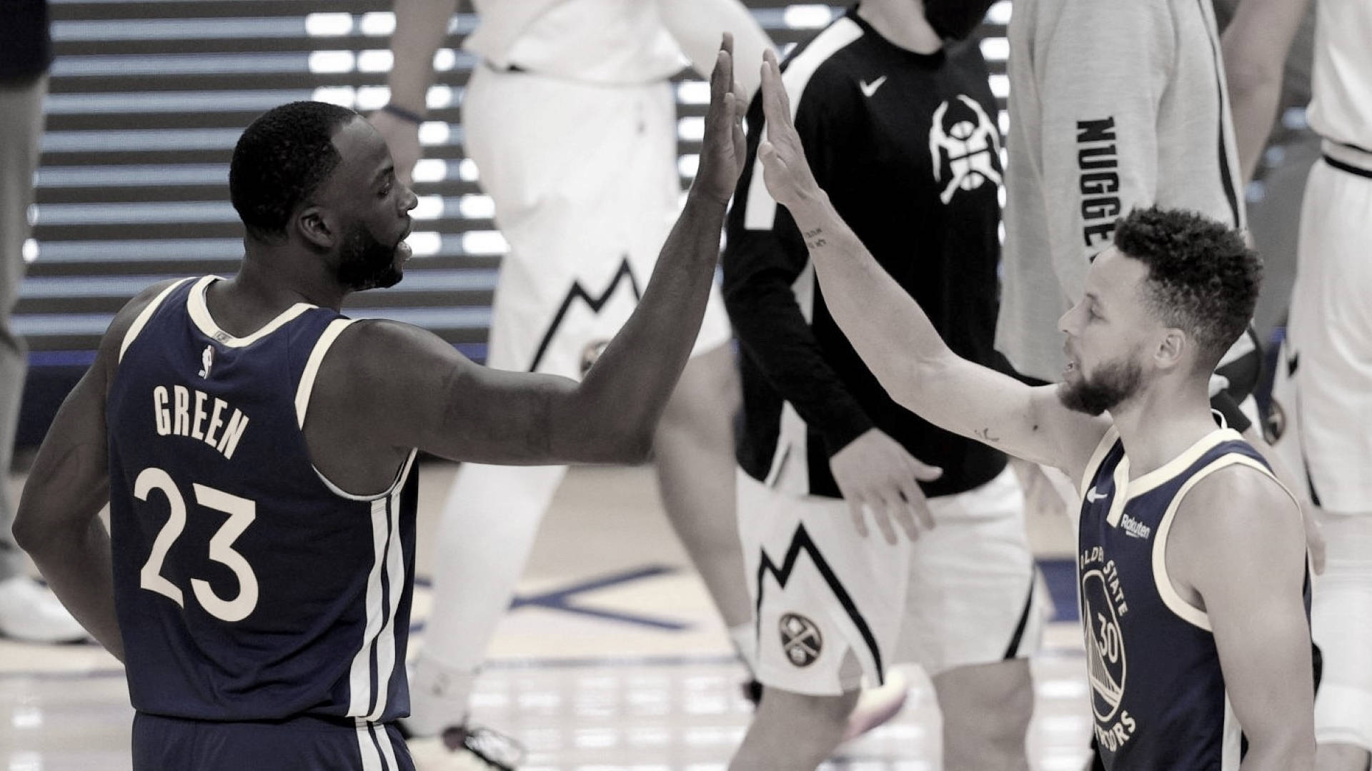 Draymond Green 桌布 壁紙 — 兩名身穿海軍藍球衣的籃球運動員在球場上擊掌，背景有隊友。