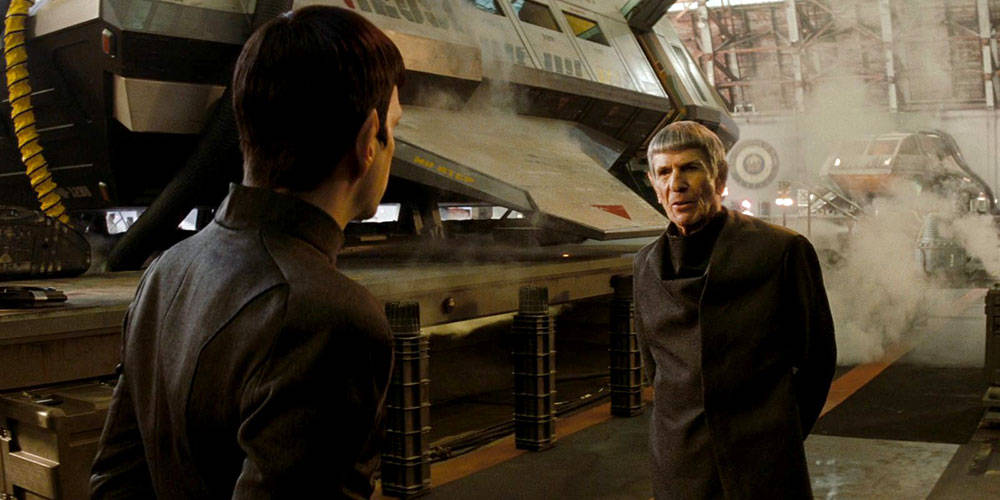Spock 桌布 壁紙 — 兩名身穿深色制服的男人在煙霧瀰漫的工業機庫裡，在一艘大型太空船旁邊交談。