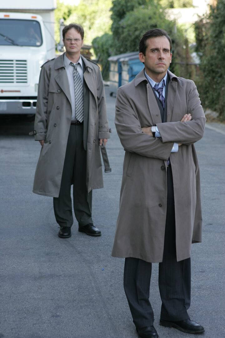 Michael Scott 桌布 壁紙 — 兩名身穿灰色風衣的男子在鋪砌的場地上交叉雙臂站立，身後有一輛白色卡車。