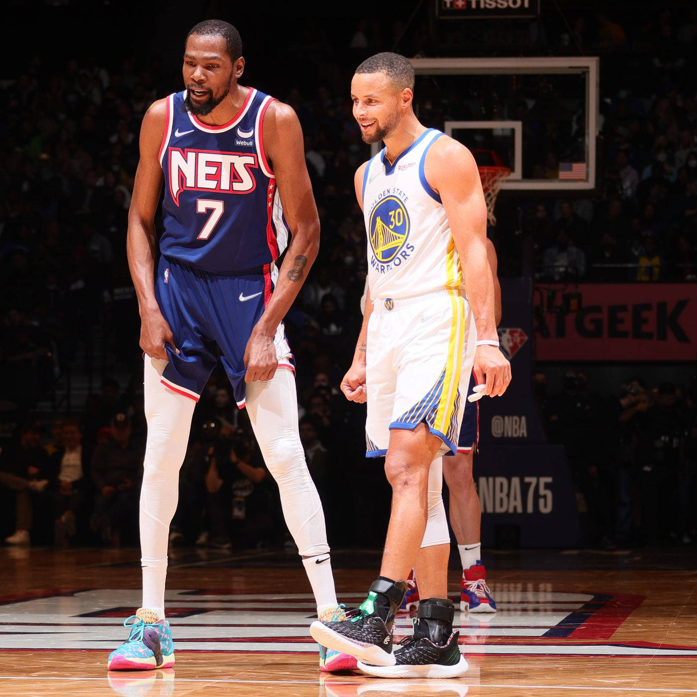 NBA 桌布 壁紙 — 兩名身穿球隊制服的NBA籃球運動員站在拋光的球場上，背景有觀眾和籃框。