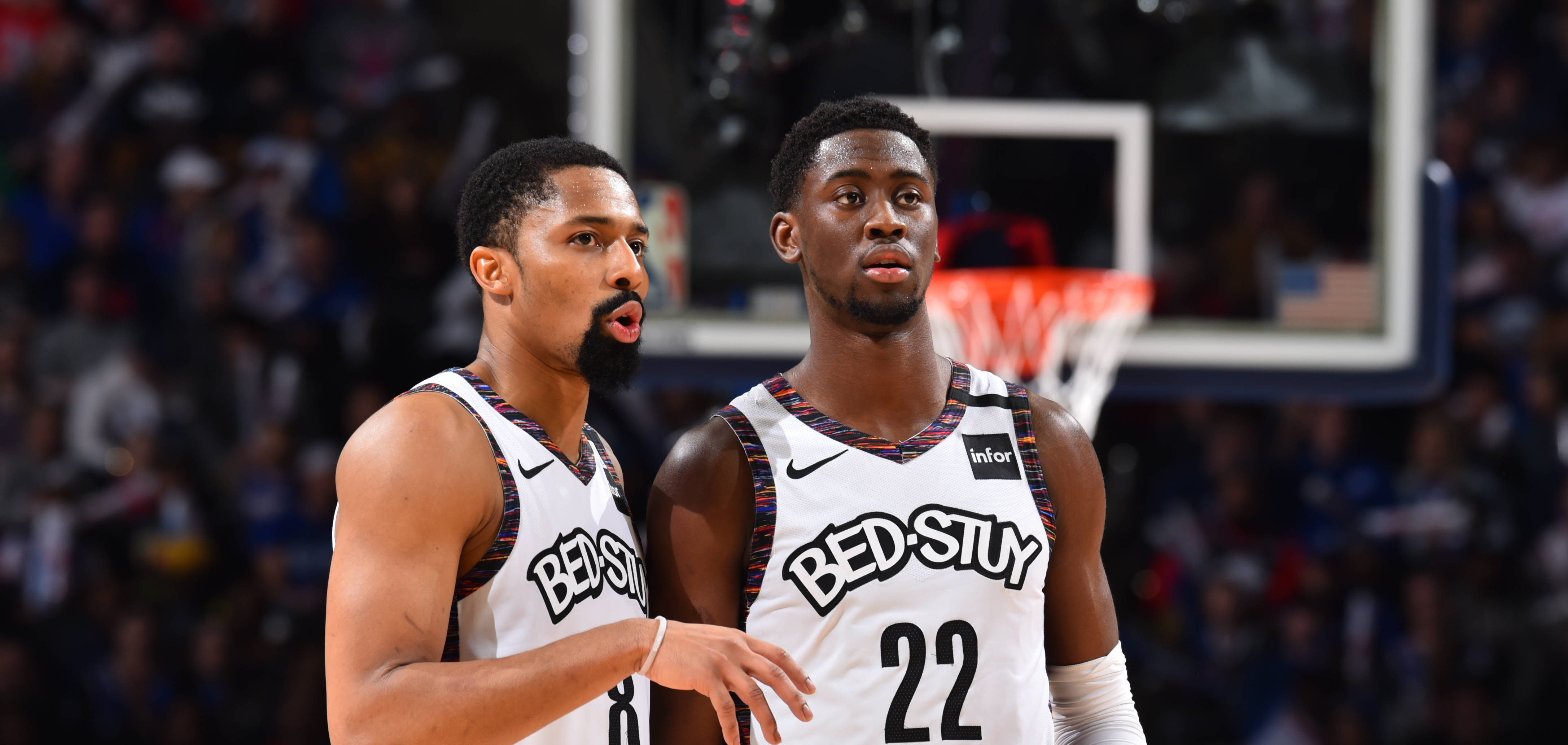 caris levert 桌布 壁紙 — 兩名身穿白色 'BEDSTUY' 球衣的籃球運動員專注地站在球場上，身後有觀眾和籃框。