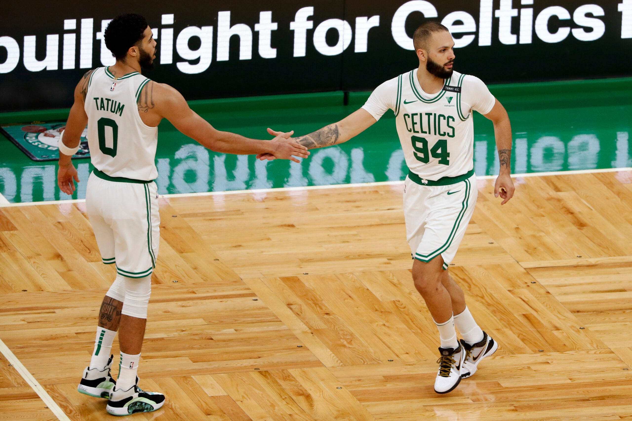 NBA 桌布 壁紙 — 兩名身穿白色和綠色球衣的波士頓塞爾提克籃球運動員在拋光木地板上握手。