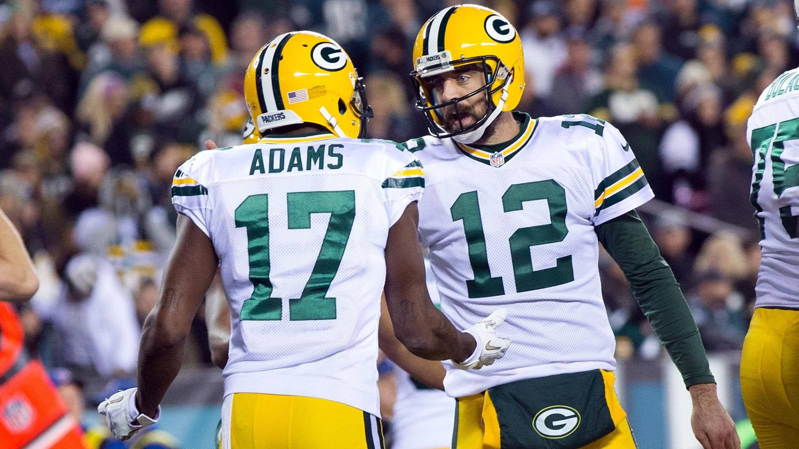 Davante Adams 桌布 壁紙 — 兩名身穿白色和綠色球衣的綠灣包裝工美式足球員在比賽中於球場上慶祝，身後是模糊的人群。
