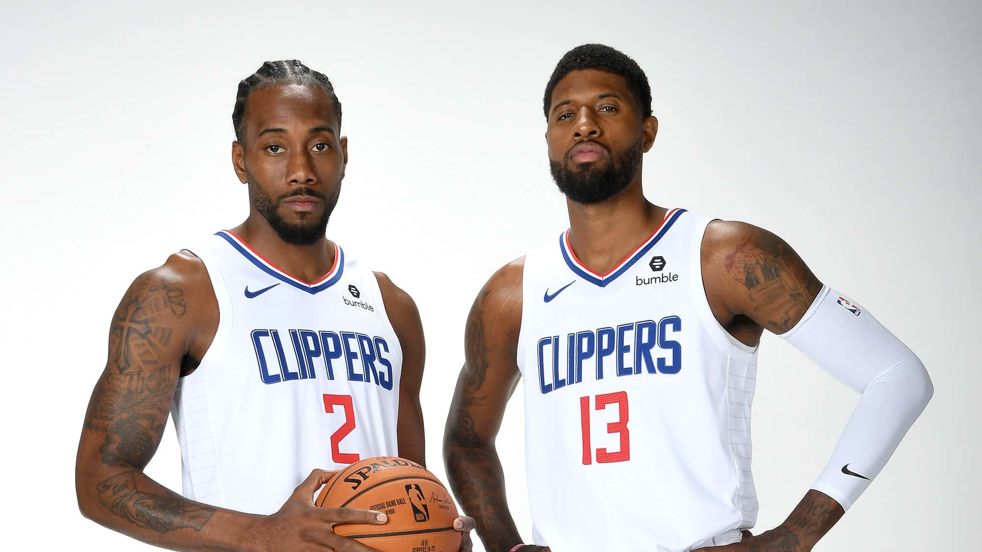 Paul George Clippers 桌布 壁紙 — 兩名身穿白色快艇隊球衣的籃球運動員在純白色背景前自信地擺姿勢，其中一人拿著籃球。