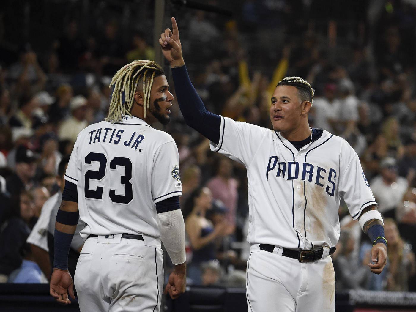 Tatis 桌布 壁紙 — 兩名身穿白色教士隊球衣的棒球選手在夜晚的歡呼人群中慶祝一個比賽，其中一人指向天空。