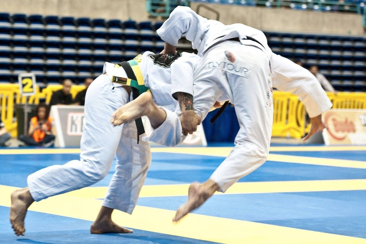 martial arts 桌布 壁紙 — 兩名身穿白色柔道服的柔道選手在藍黃色墊子上激烈纏鬥，進行一場競技比賽。