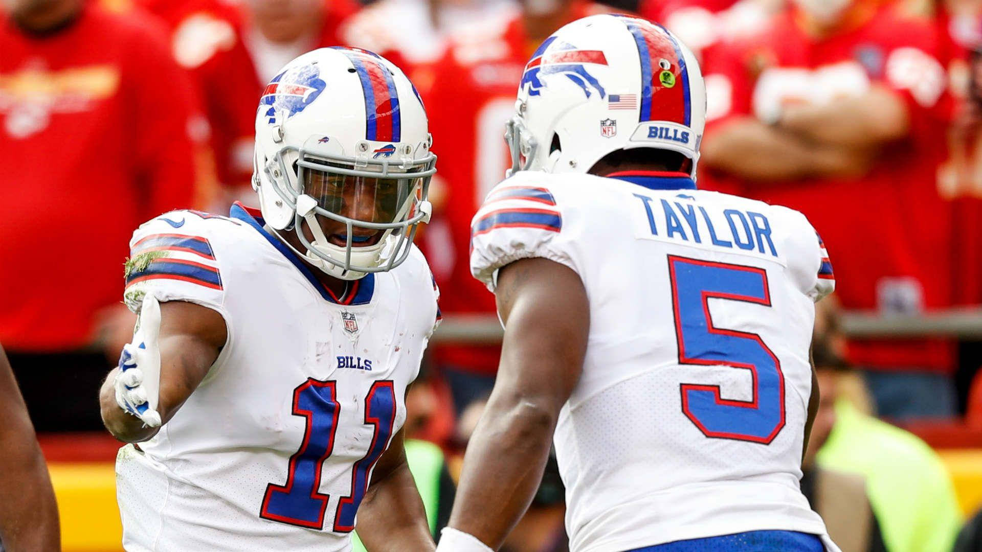 zay jones 桌布 壁紙 — 兩名身穿白色球衣、帶有藍紅配色的水牛城比爾美式足球球員在陽光明媚的比賽場地上慶祝。