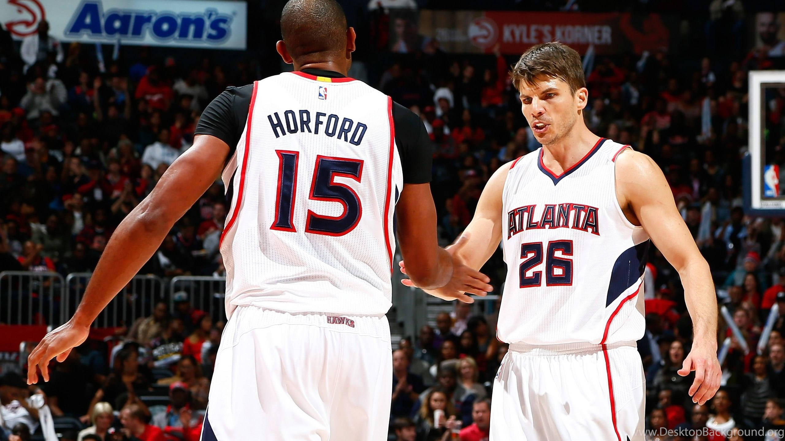 Al Horford 桌布 壁紙 — 兩名身穿白色球衣的亞特蘭大老鷹隊籃球運動員在擠滿人的球場上比賽期間握手。