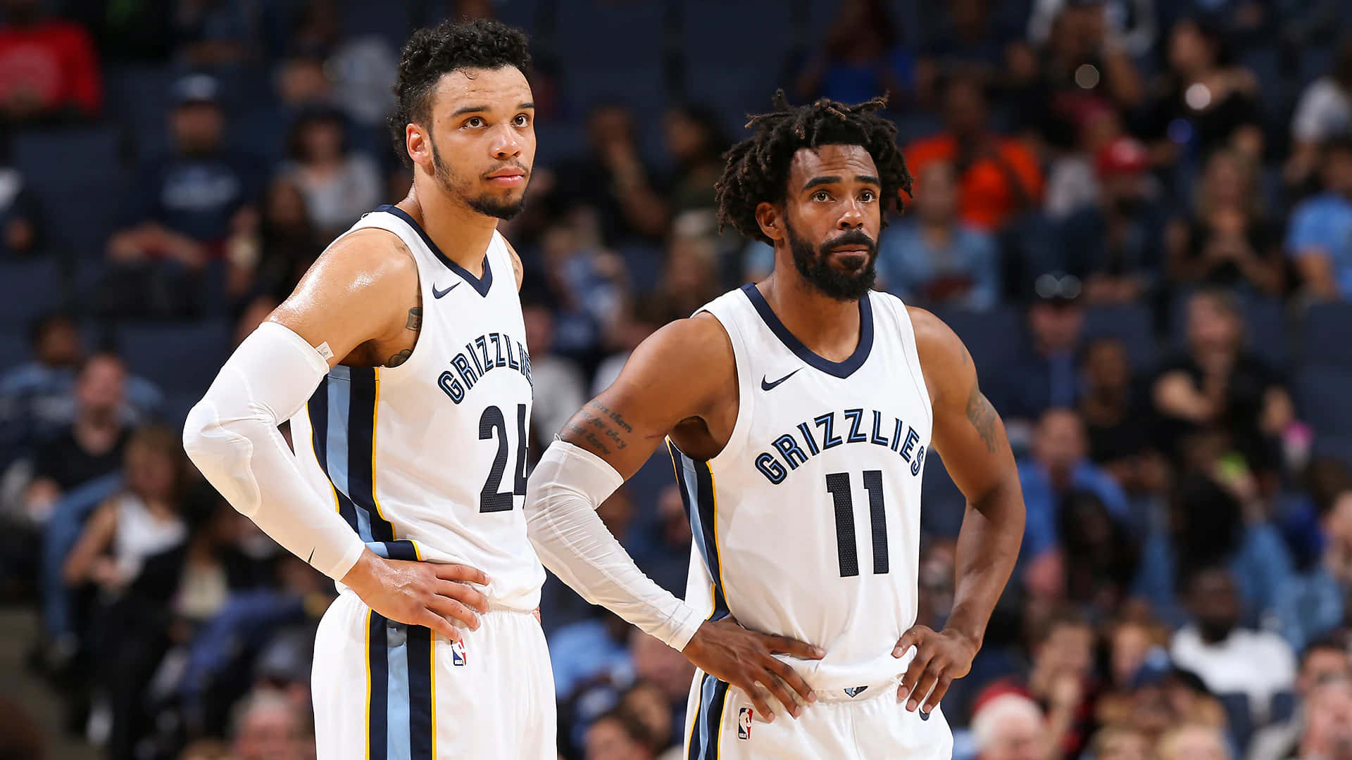 Dillon Brooks 桌布 壁紙 — 兩名身穿白色球衣的曼菲斯灰熊籃球運動員在比賽中雙手叉腰站立，身後是模糊的人群。