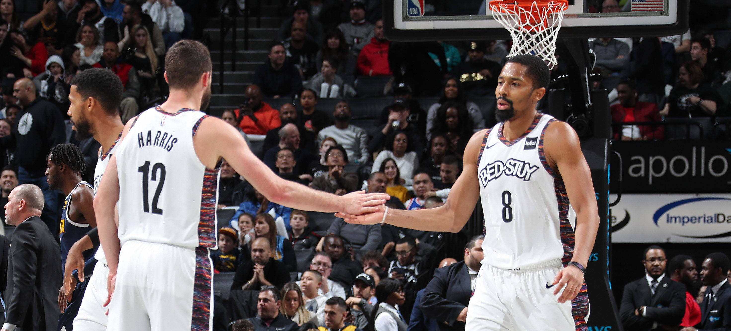 spencer dinwiddie 桌布 壁紙 — 兩名身穿白色球衣的籃球運動員在籃框下握手，觀眾專注地觀看。