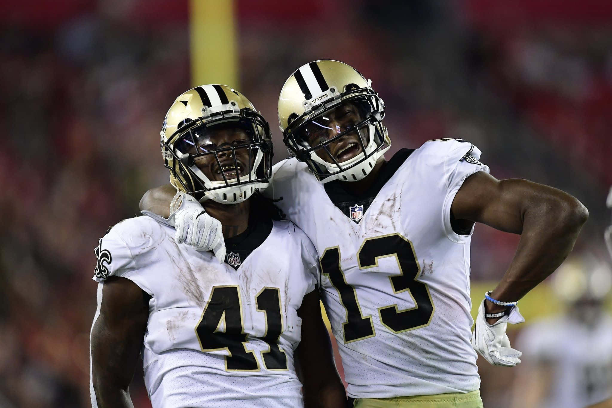 Alvin Kamara 桌布 壁紙 — 兩名身穿白色球衣的紐奧良聖徒隊美式足球球員在球場燈光下激烈慶祝。