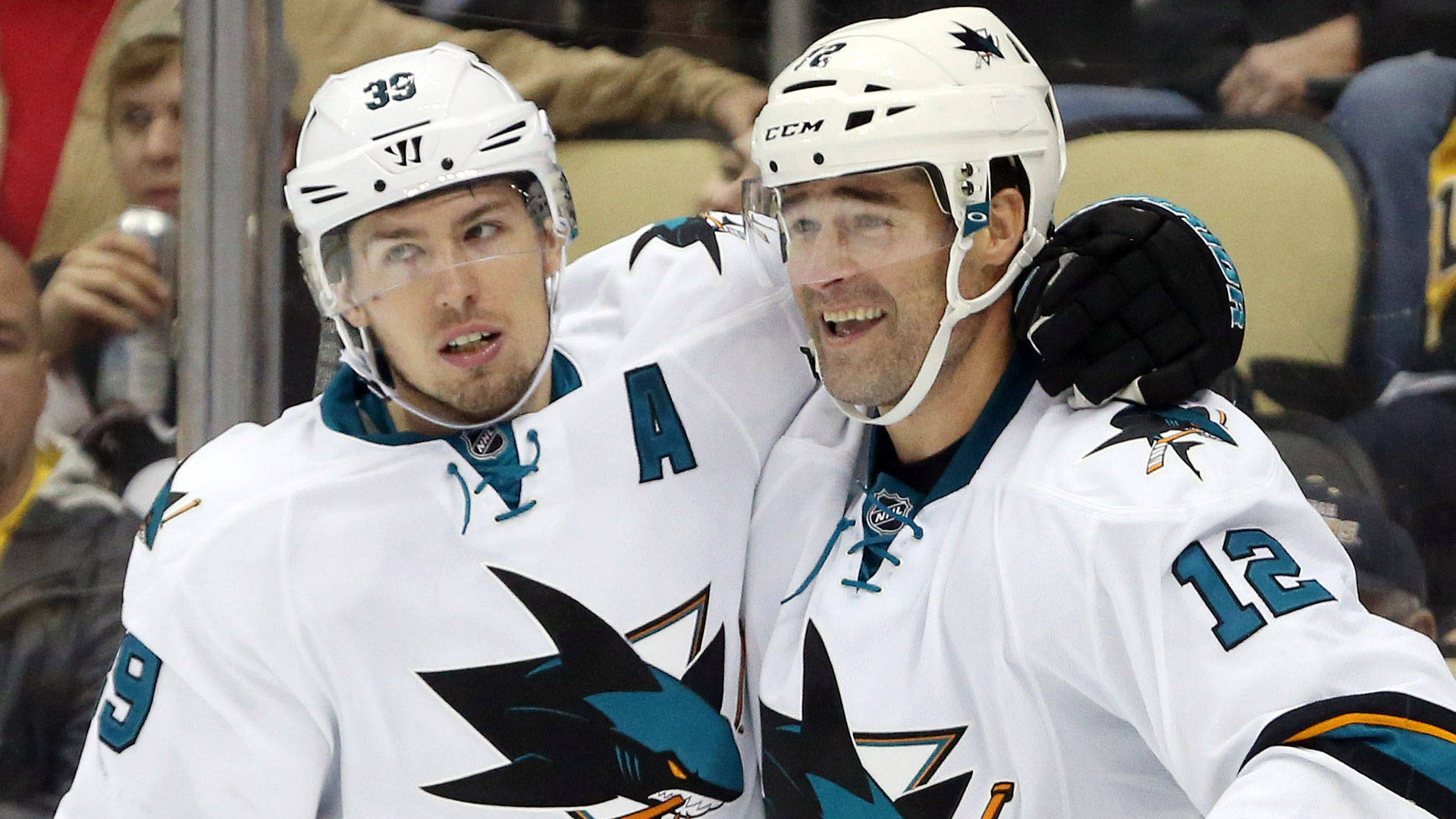hockey 桌布 壁紙 — 兩名身穿白色球衣的聖荷西鯊魚隊冰球球員在冰上互相擁抱慶祝。
