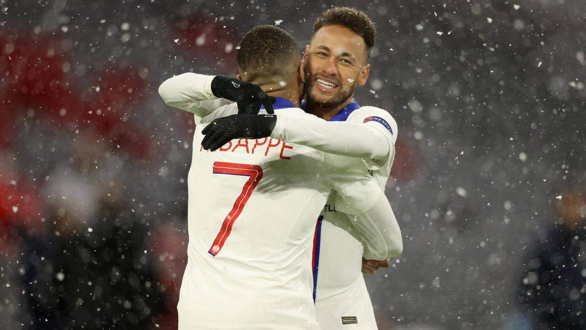 Football Players 桌布 壁紙 — 兩名身穿白色球衣的足球員在夜間比賽中，雪花飄落時歡喜地擁抱。
