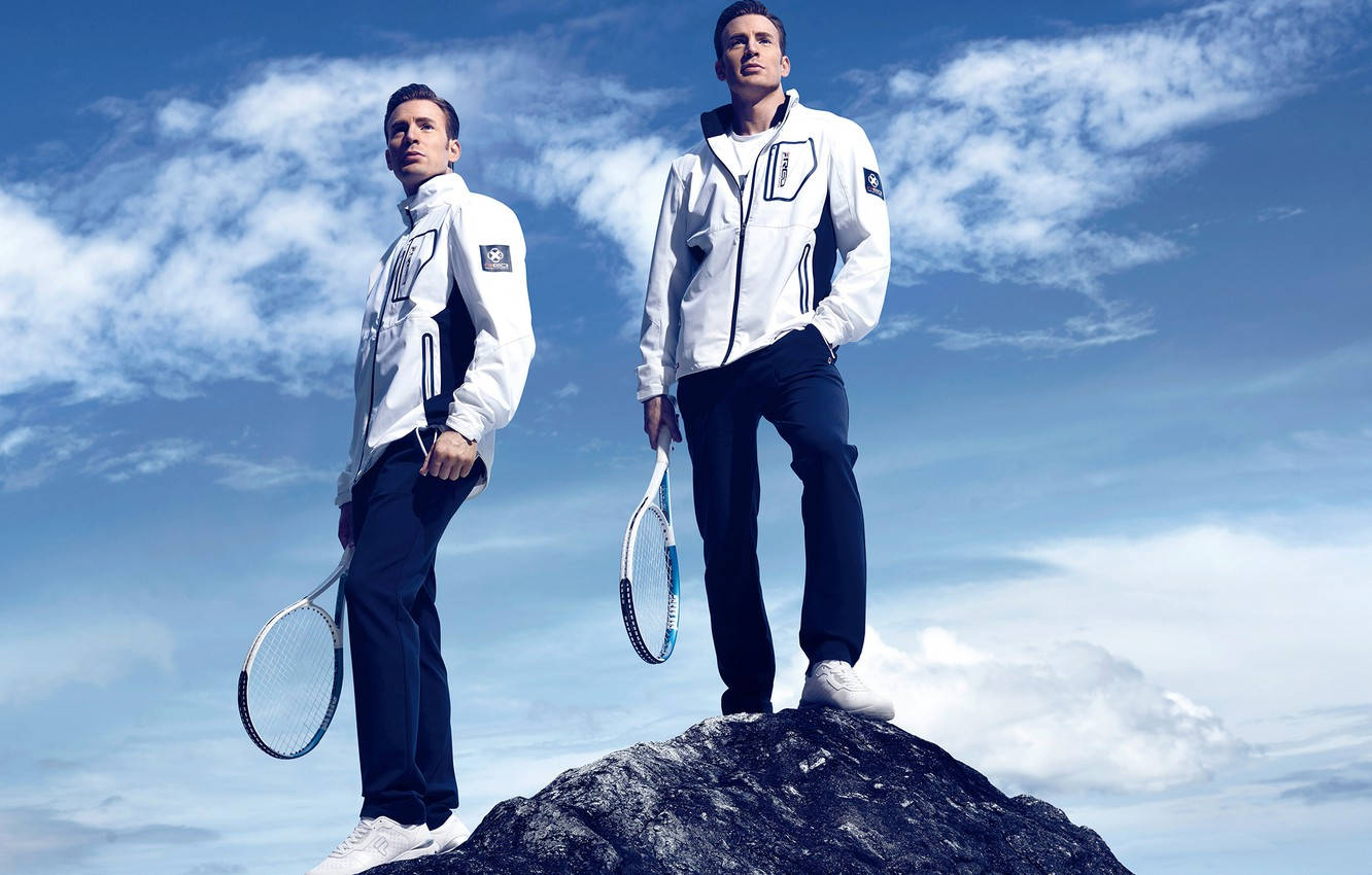 Fila 桌布 壁紙 — 兩名身穿白色網球外套的男子站在岩石頂峰，在廣闊藍天和零星雲朵下手持球拍。