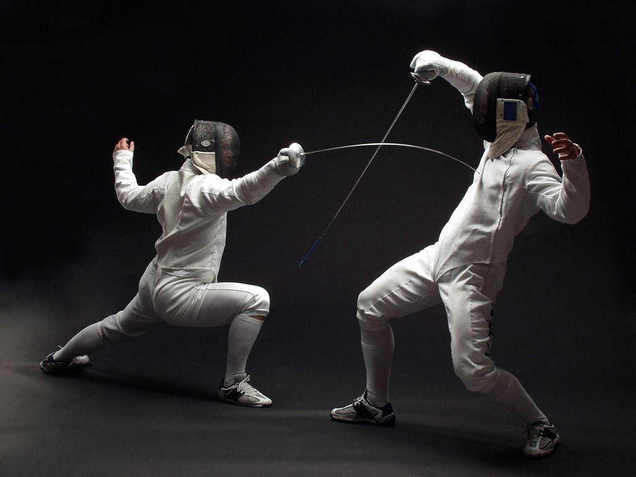 Fencing 桌布 壁紙 — 兩名身穿白色裝備的劍擊手在黑暗煙霧繚繞的背景前，於戲劇性的攝影棚拍攝中交鋒。
